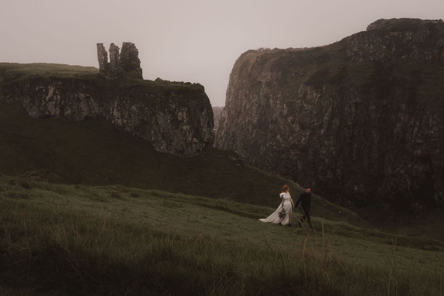 A elopement on a rugged green hillside with dramatic cliffs and rock formations on the Northern Ireland Coast