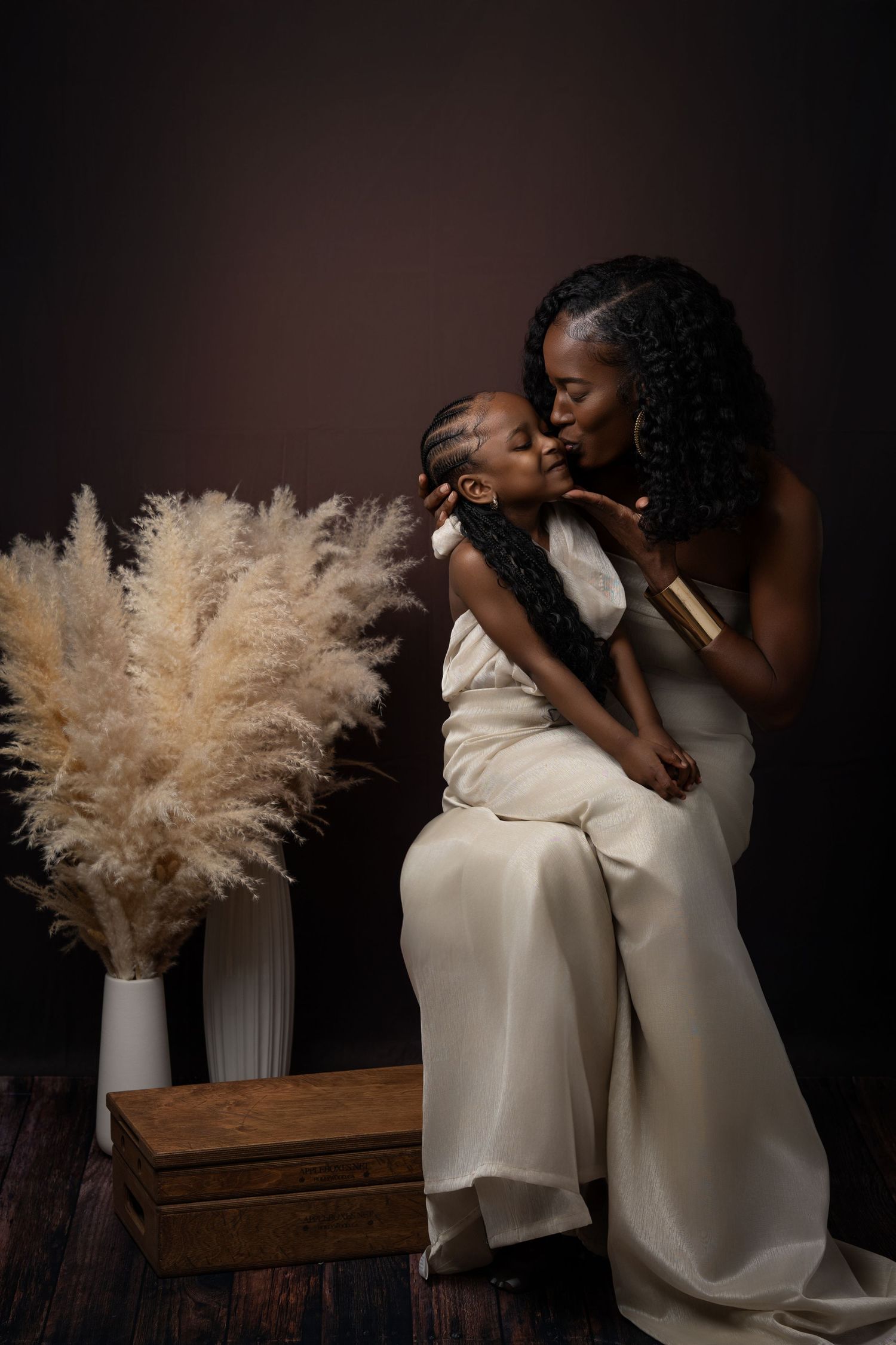 An artistic black and white photography series showing two people in white dresses posing intimately with pampas grass decor.