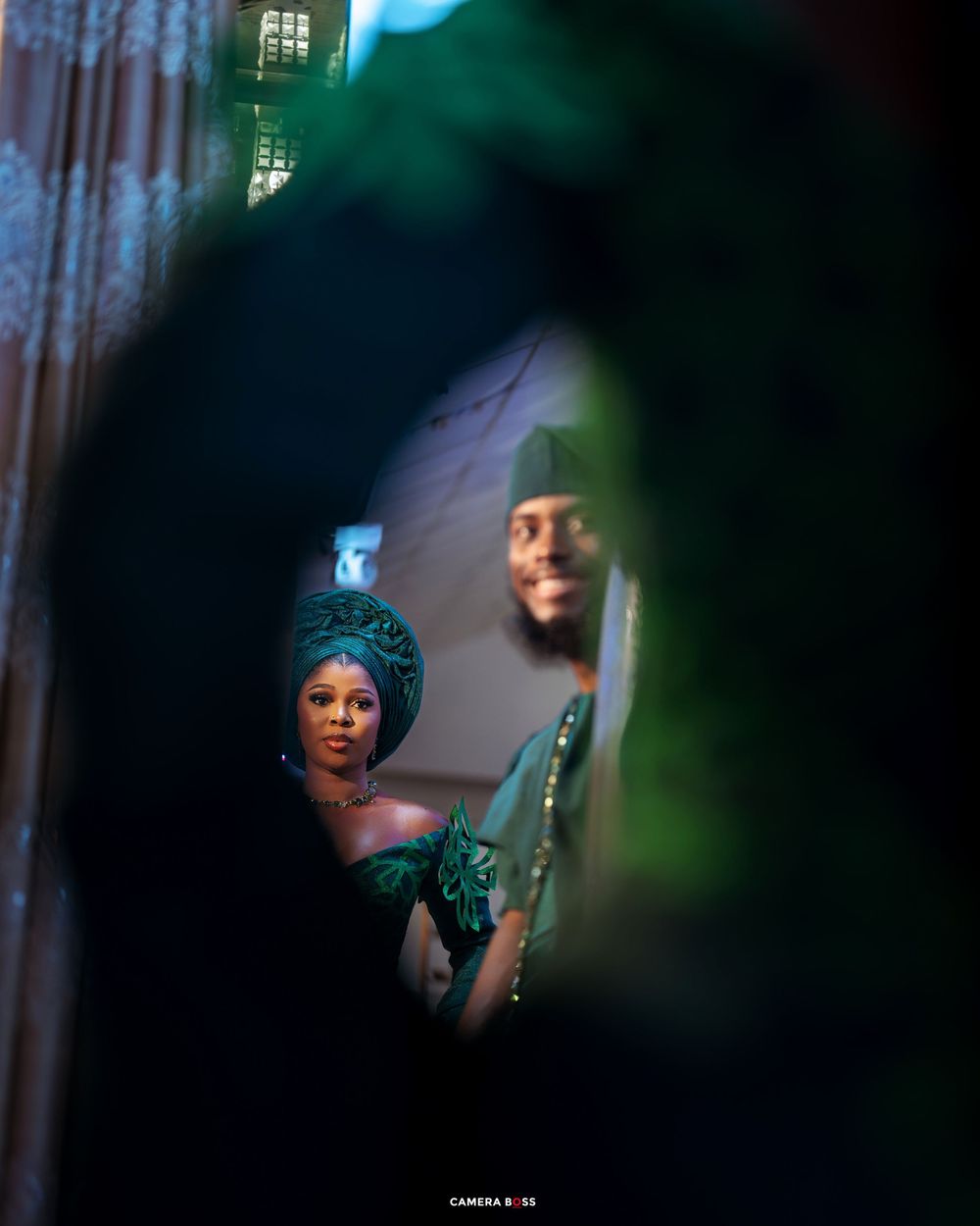 Looking through green-tinted leaves, a stylish gathering is captured in dramatic lighting and shadows.