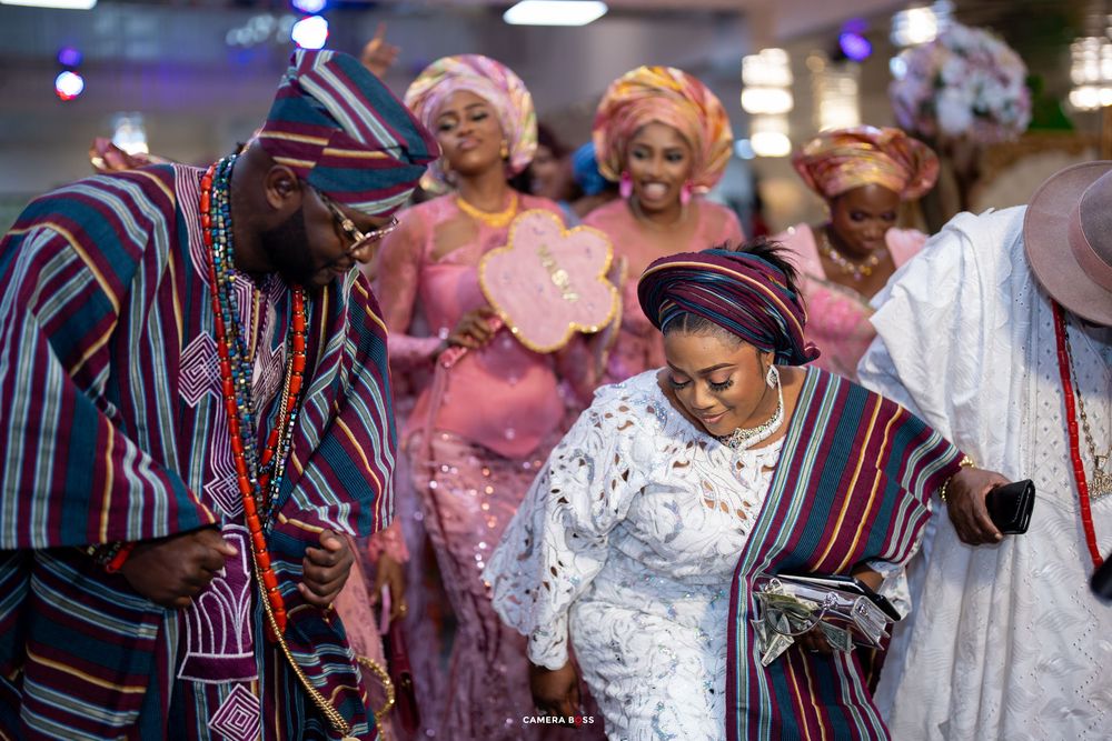 Traditional Nigerian wedding celebration with people wearing colorful agbada and aso oke attire during a joyful ceremony.