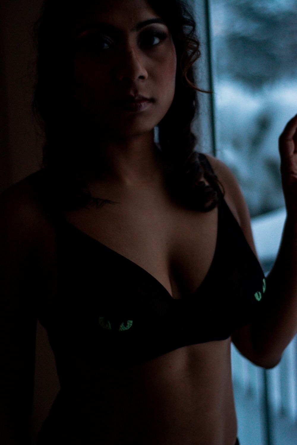 Dramatic low-light portrait against window with moody evening atmosphere.