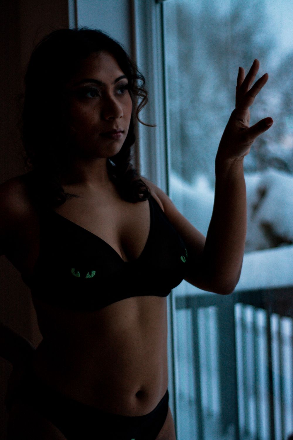 Artistic portrait with window lighting creating dramatic shadows and mood.