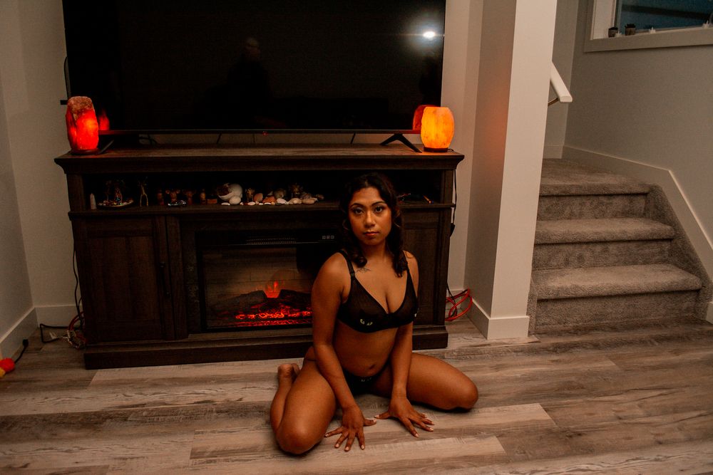 Indoor portrait near fireplace with decorative lighting and wooden flooring.