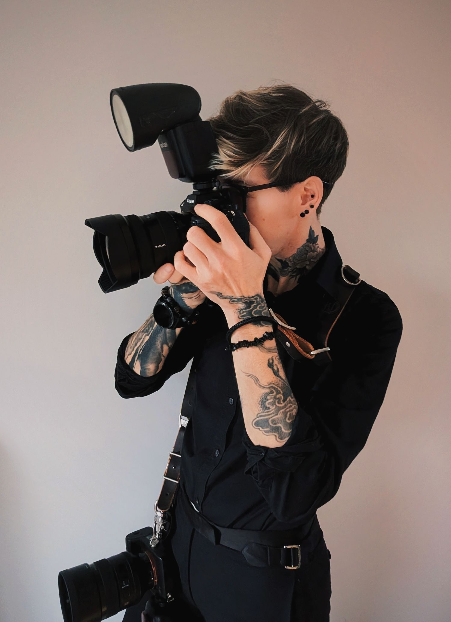 Photographer in black clothing using professional camera with mounted flash.