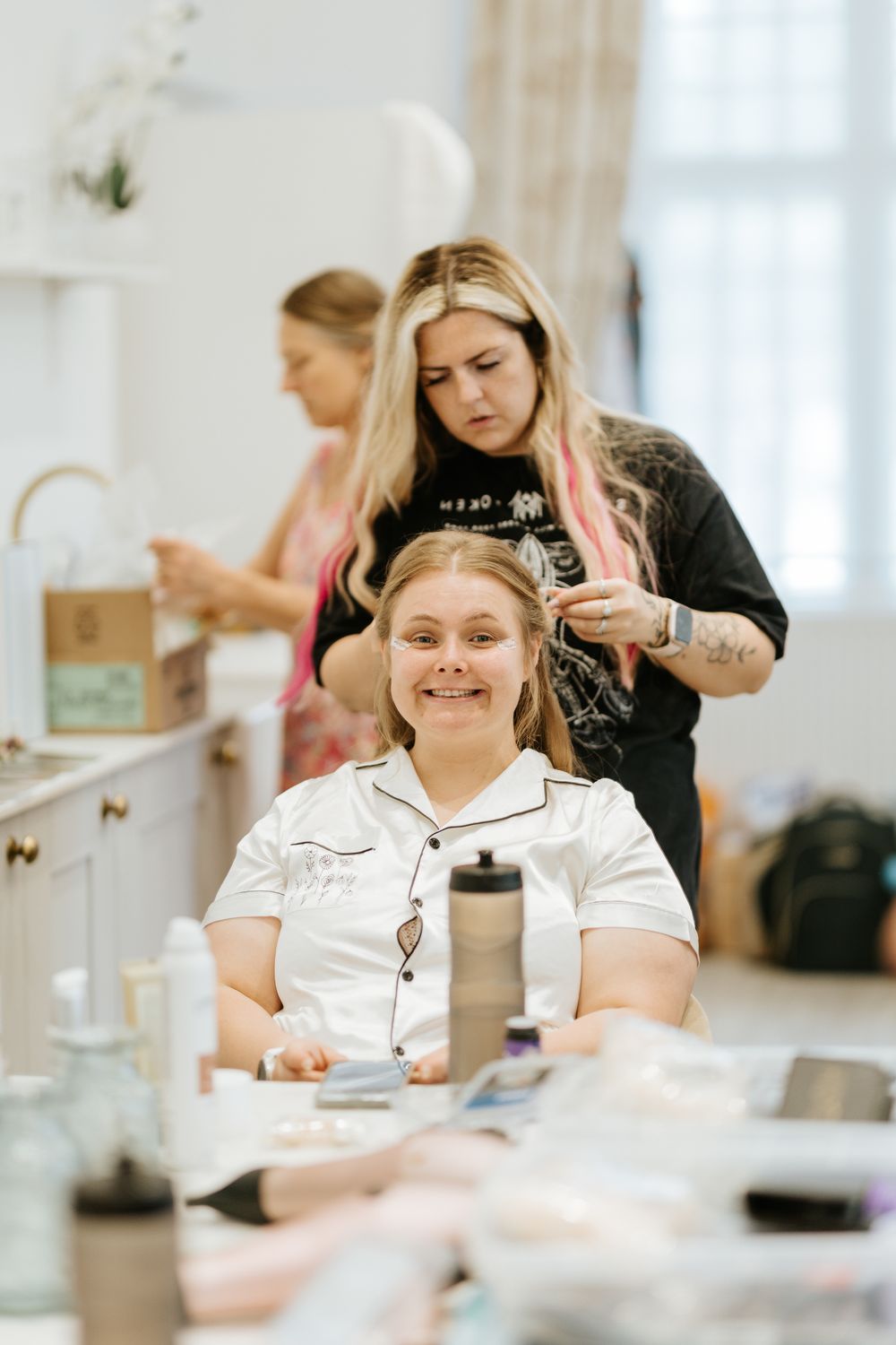 Woman in white getting hair and makeup done at a bright, modern salon.