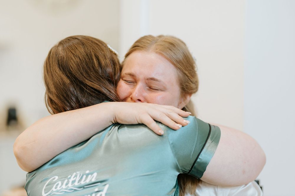 Emotional wedding moment captured as couple shares tight embrace with family members during celebration.