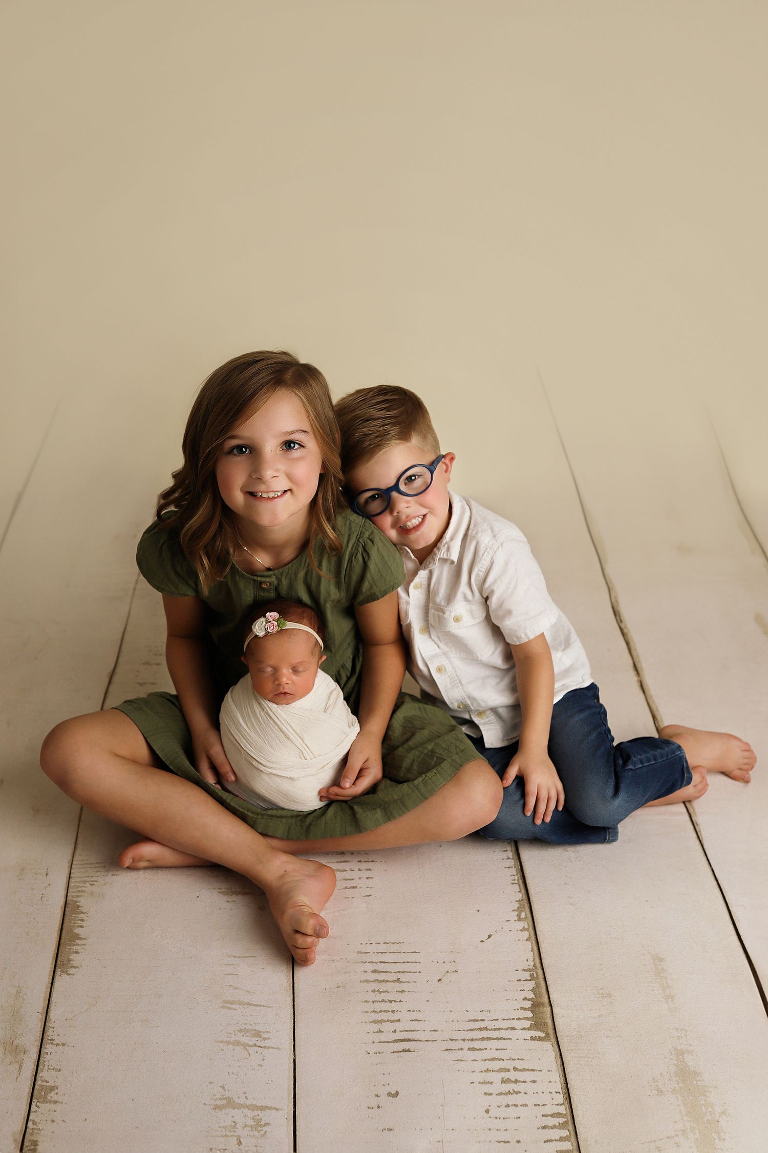 A series of five artistic lifestyle photos of a family group arranged on white wooden floorboards.