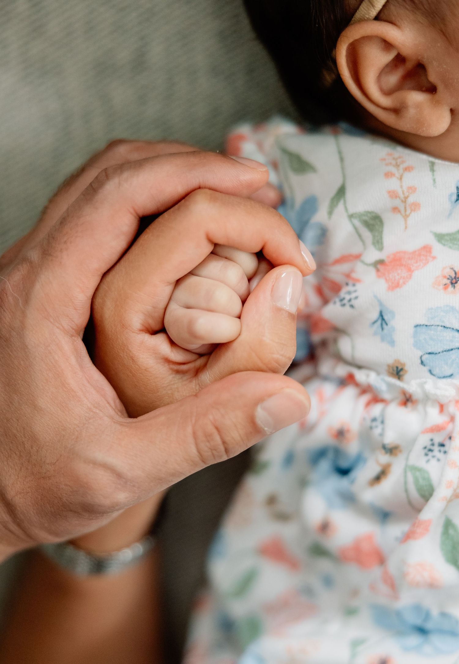 Close-up series of small hands holding fabric with delicate blue and coral floral pattern on white background.