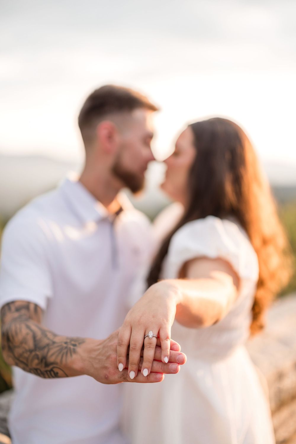 A close-up shot shows hands with an engagement ring while a couple embraces in warm sunset lighting.