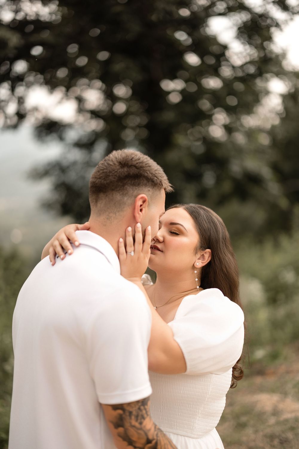 Romantic couple in white outfits sharing intimate kisses against a soft bokeh outdoor background, shown in a series of images.
