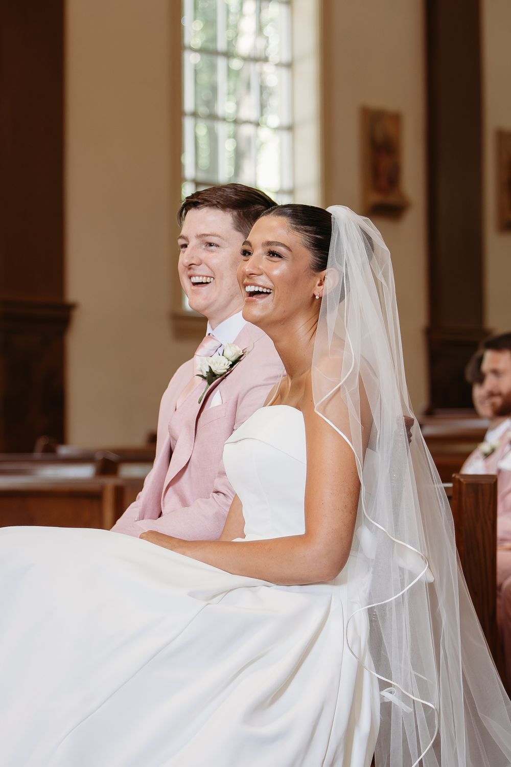 A joyful moment captured at a wedding showing a couple laughing together in a church setting.