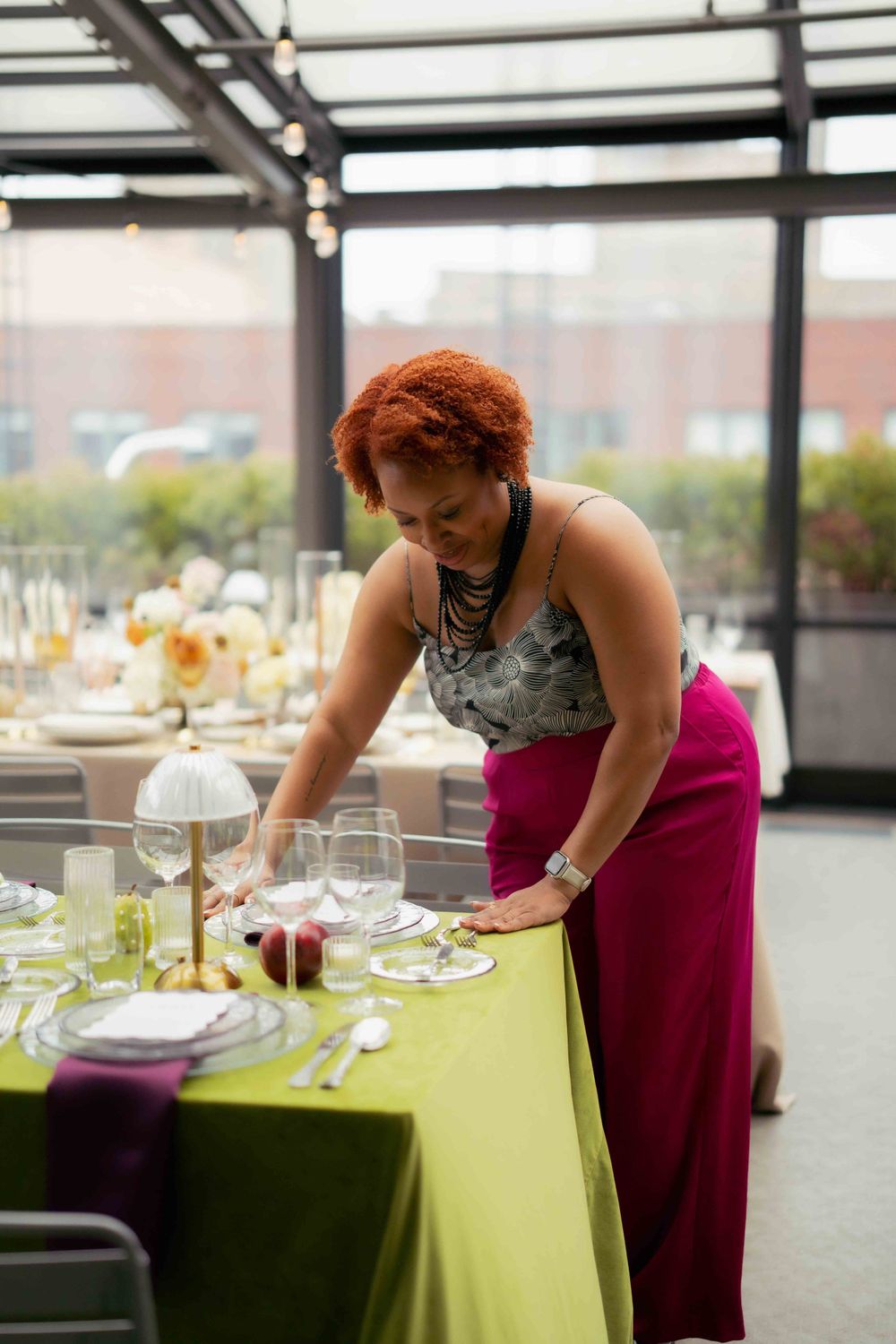 Event planner arranging table settings at an elegantly decorated reception venue.