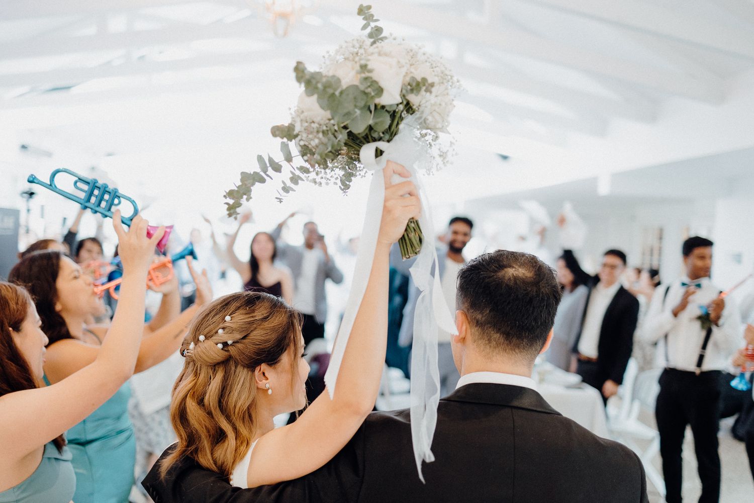 Wedding guests celebrate and raise their hands during a reception captured by Apertured Media Auckland Wedding Photographer.