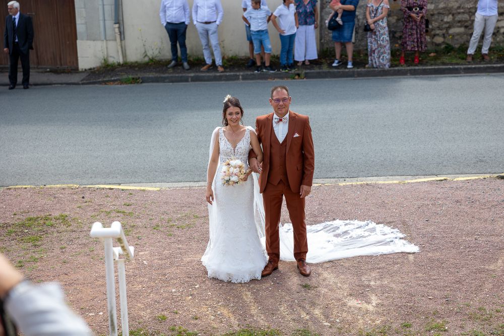 A wedding couple poses together outdoors on a summer day.