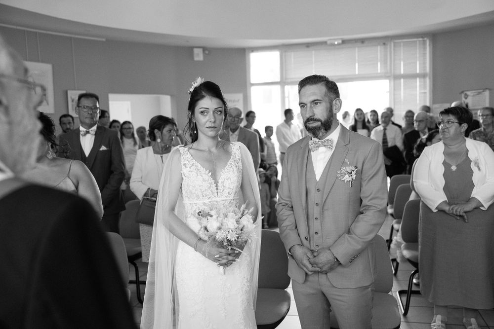 Indoor wedding ceremony with guests seated in rows of chairs.