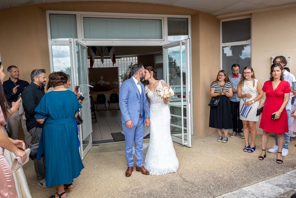 Wedding party gathered outside venue entrance with guests looking on.