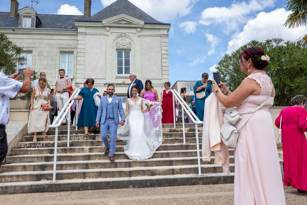 Wedding party descending grand stone steps of elegant French chateau.