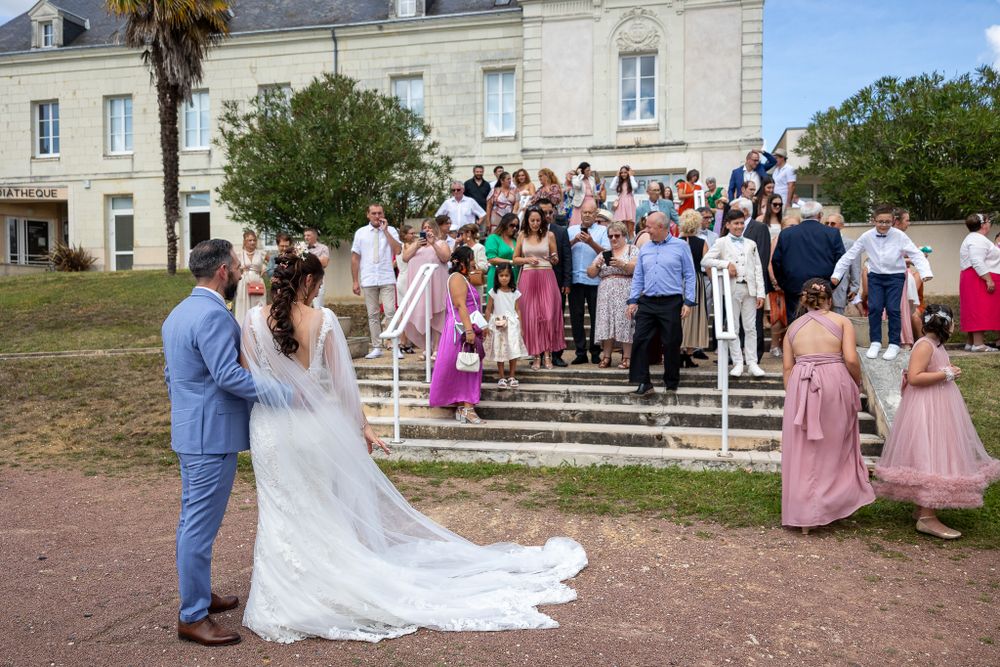 Outdoor wedding celebration on steps of historic mansion with gathered guests.