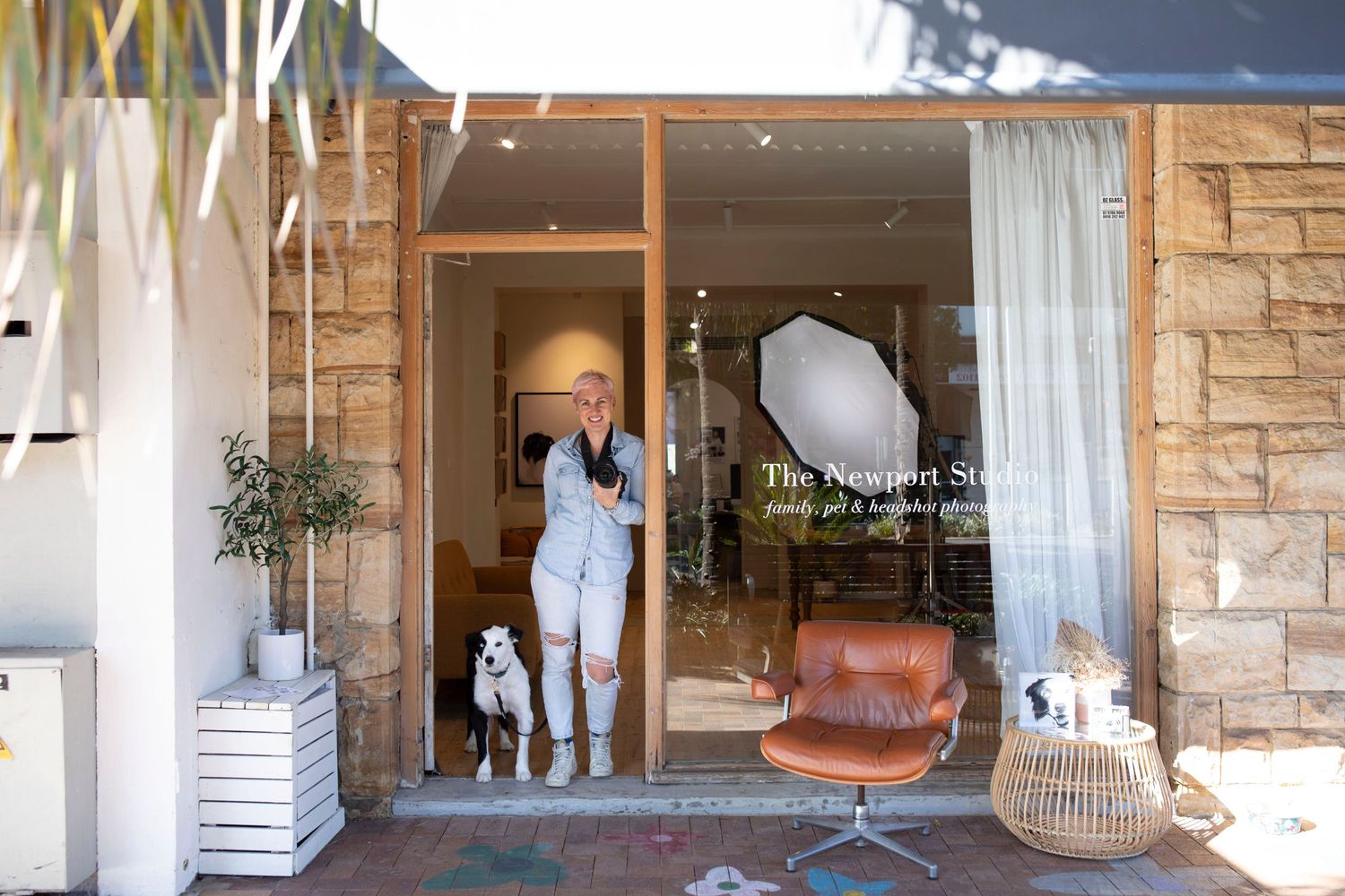 Modern storefront with glass windows, white curtains, and leather chair visible inside.