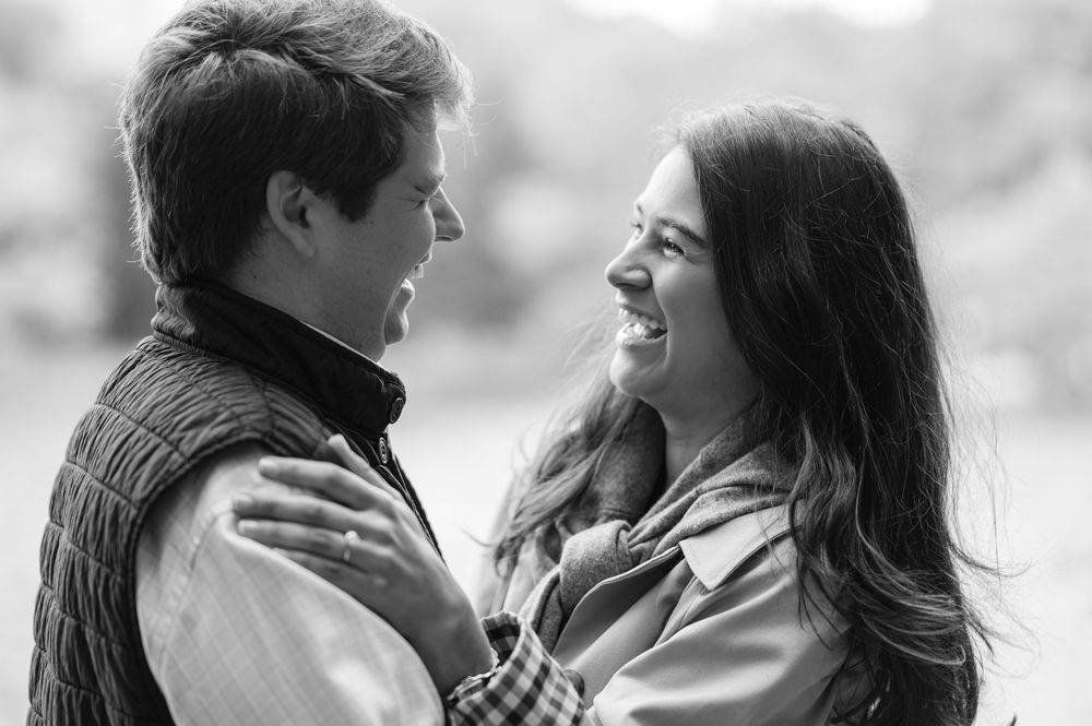 A black and white photo of two people in an intimate embrace, smiling at each other outdoors in Central Park by NYC proposal photographer