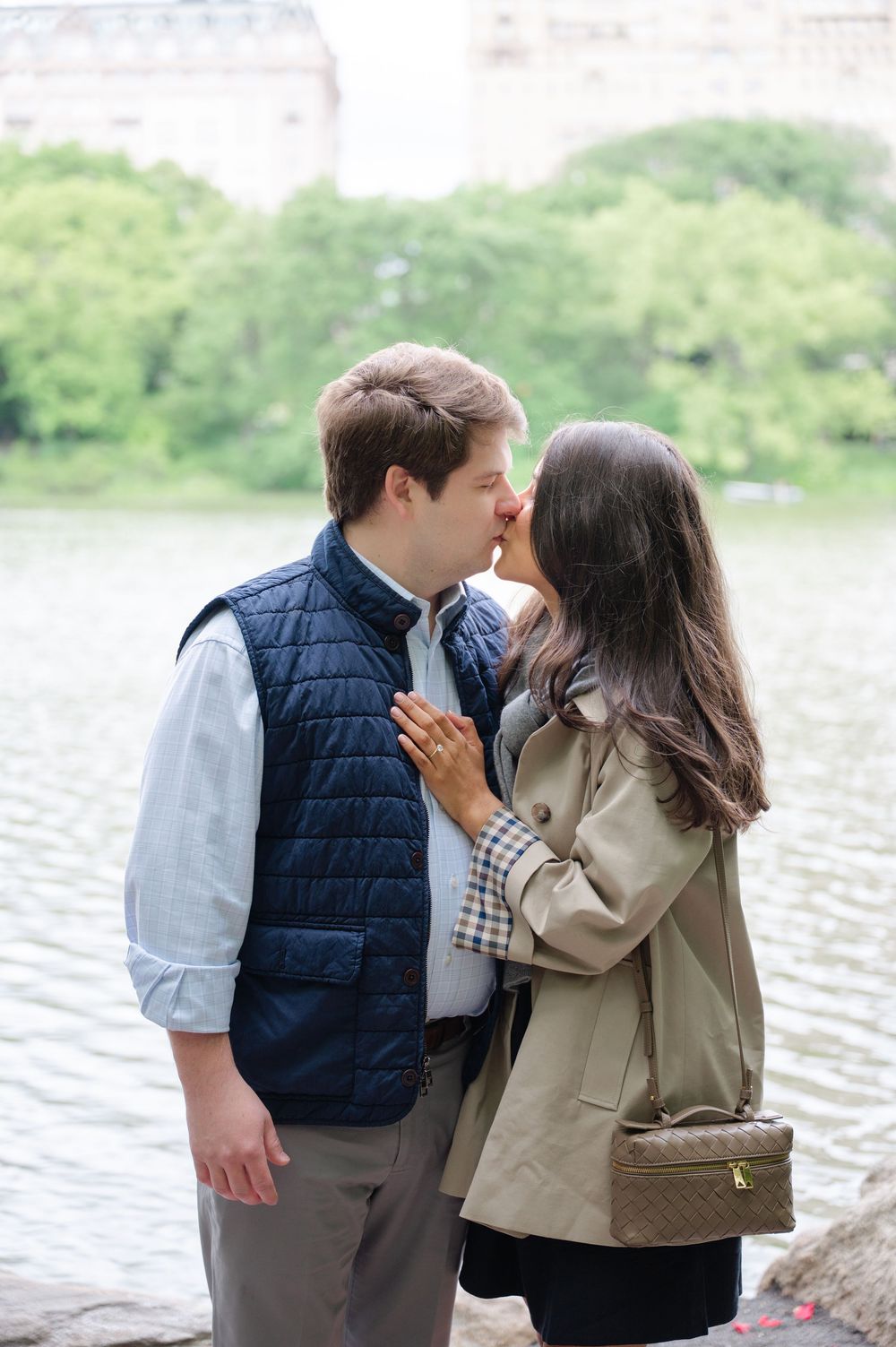 A couple shares a kiss by a lake in Central Park after their proposal. Photo by Joliette Marie Photography.