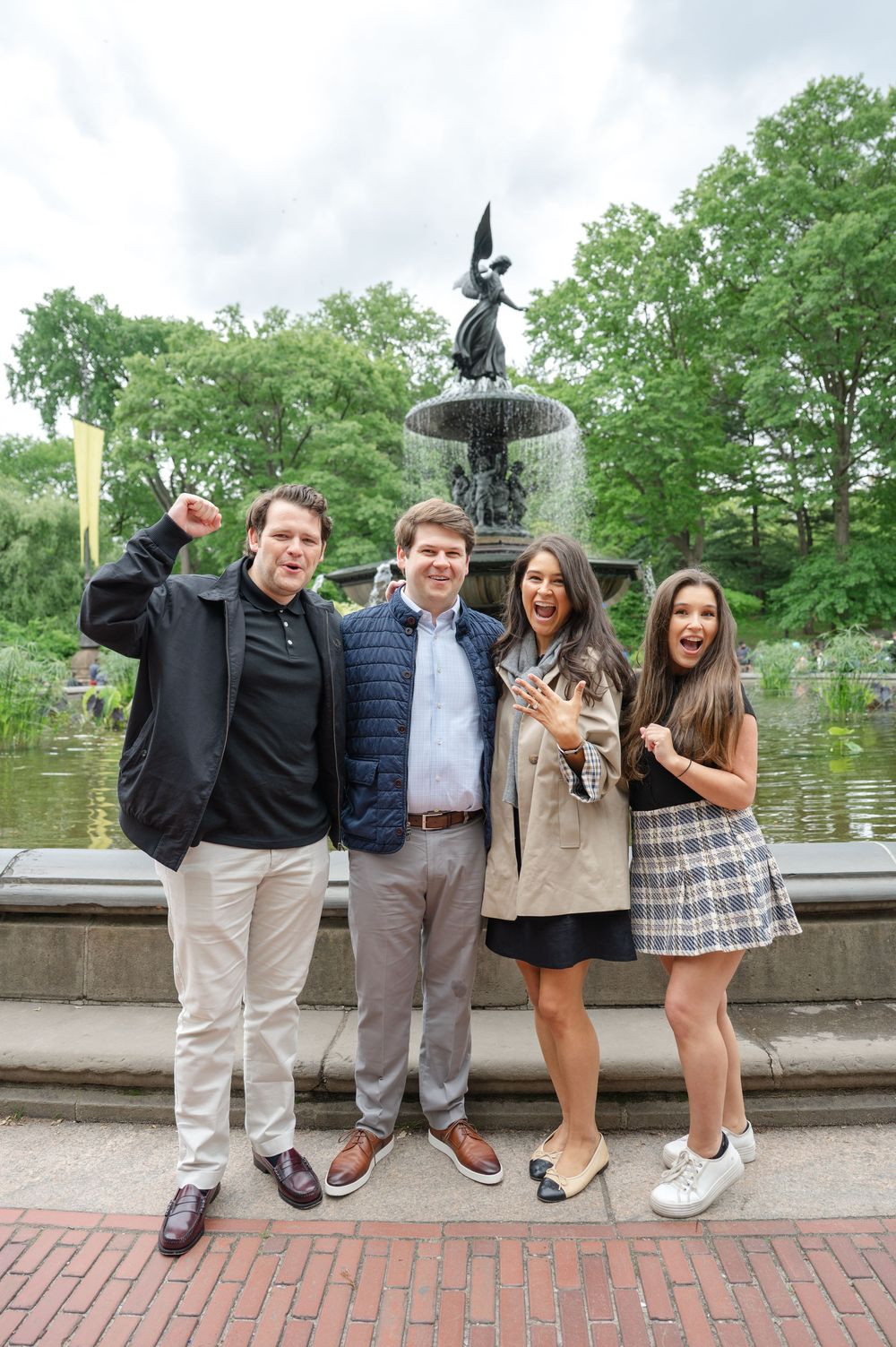 Group photo of friends posing together in front of Bethesda Fountain in Central Park, New York City after their NYC proposal