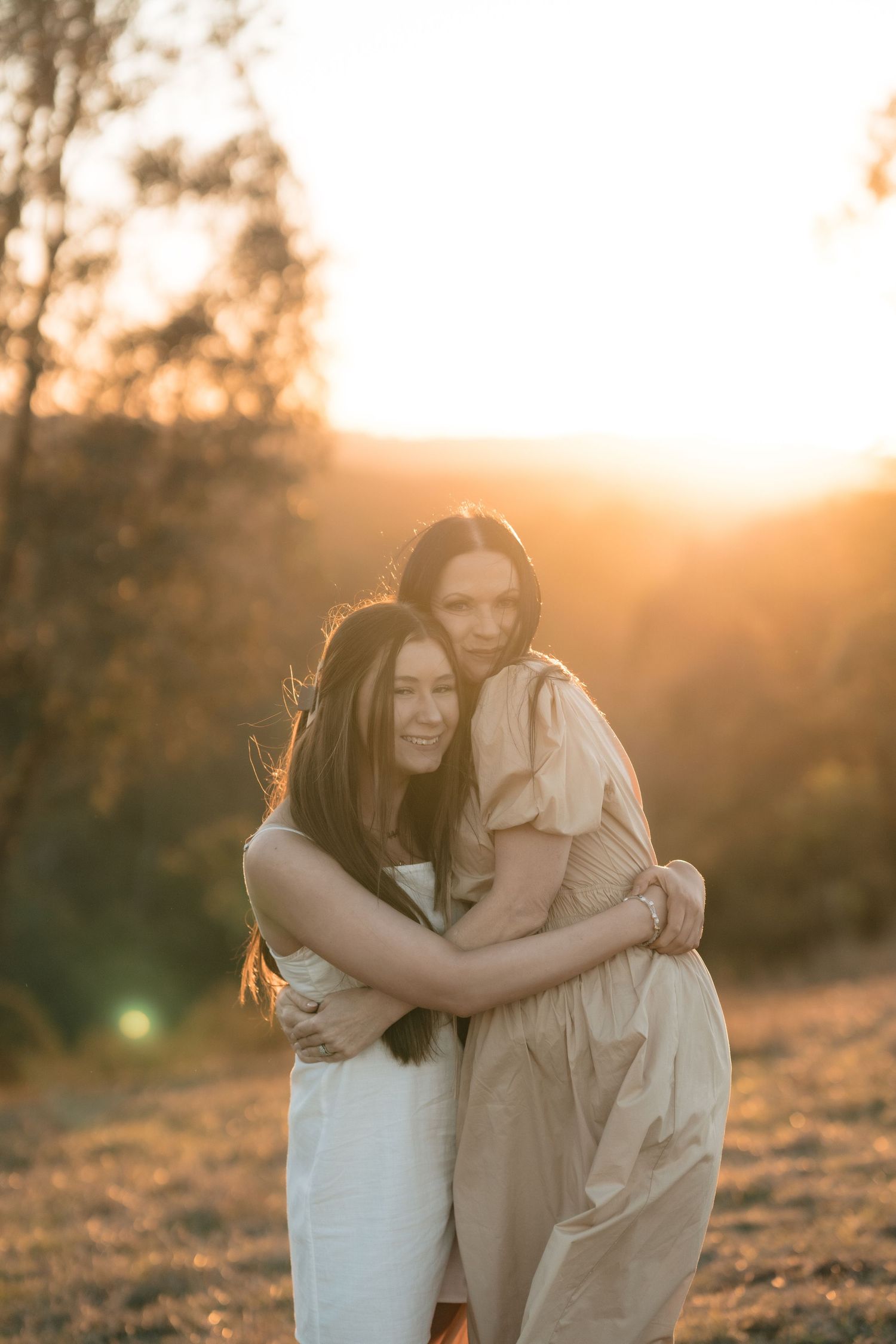 Two people sharing a warm embrace during golden hour sunset in an outdoor setting.