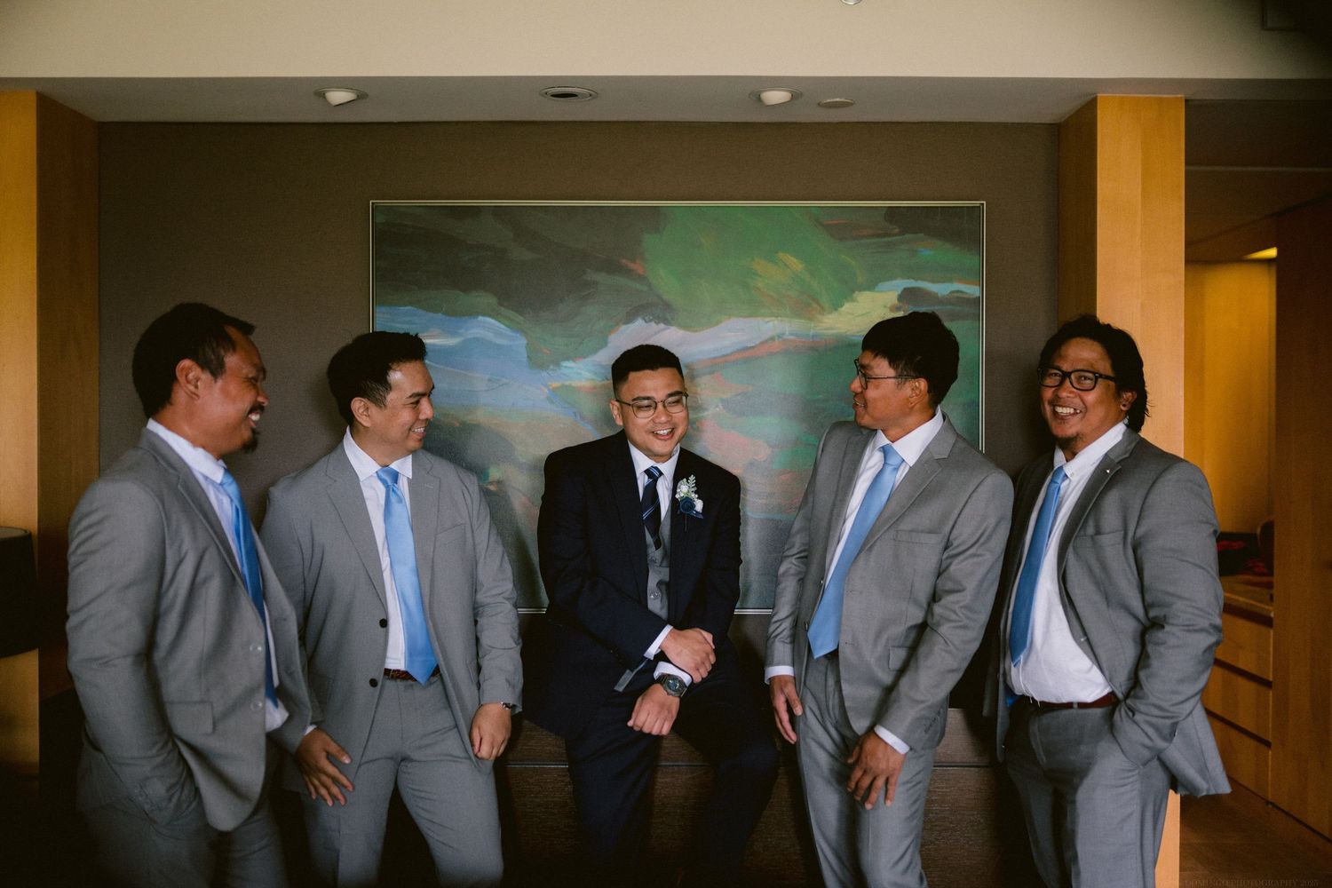 Groomsmen in grey suits gather for a casual moment before the wedding ceremony.
