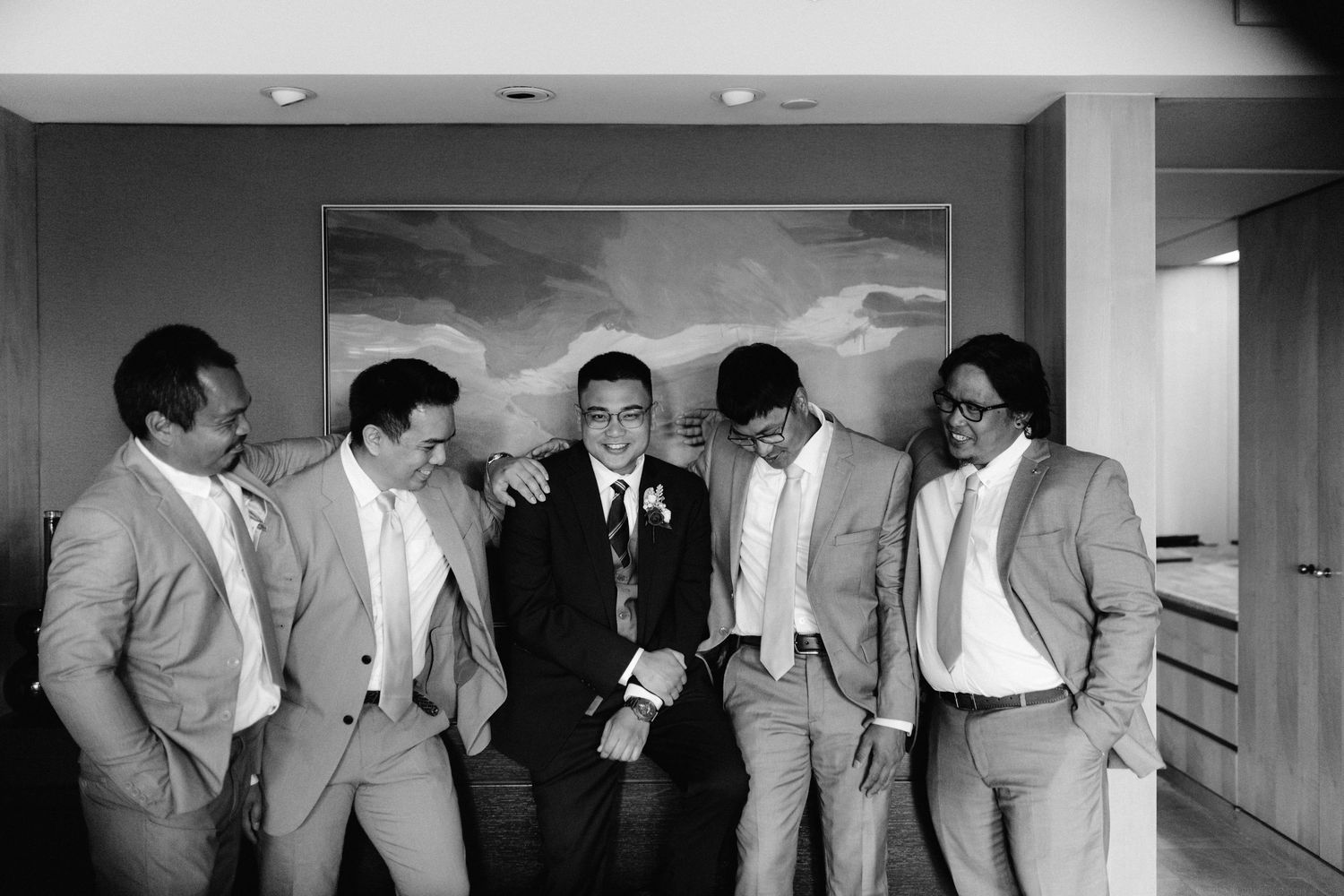 A group of groomsmen in gray suits share a candid moment.