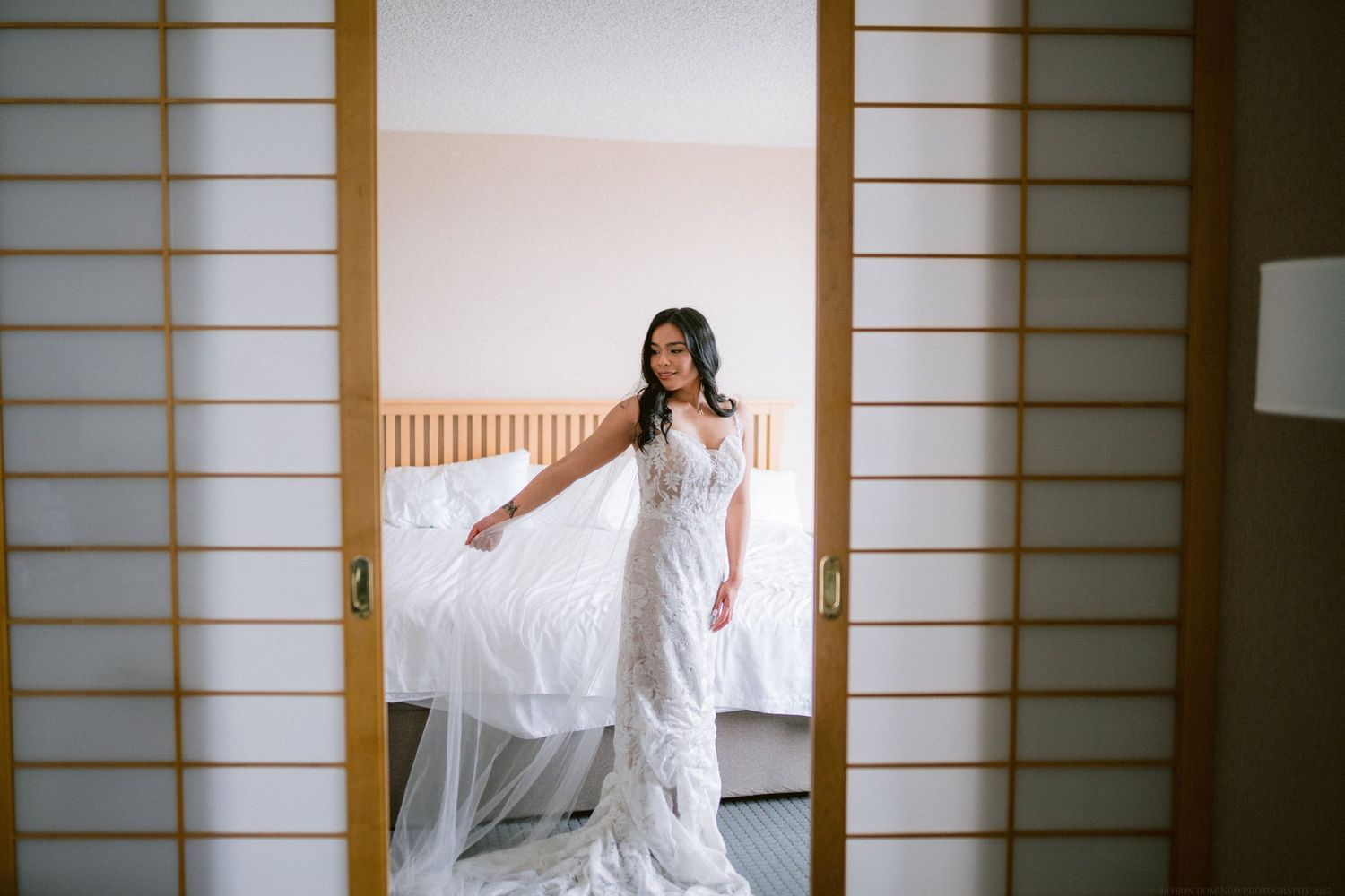 A bride poses elegantly in a white gown against traditional Japanese sliding doors.