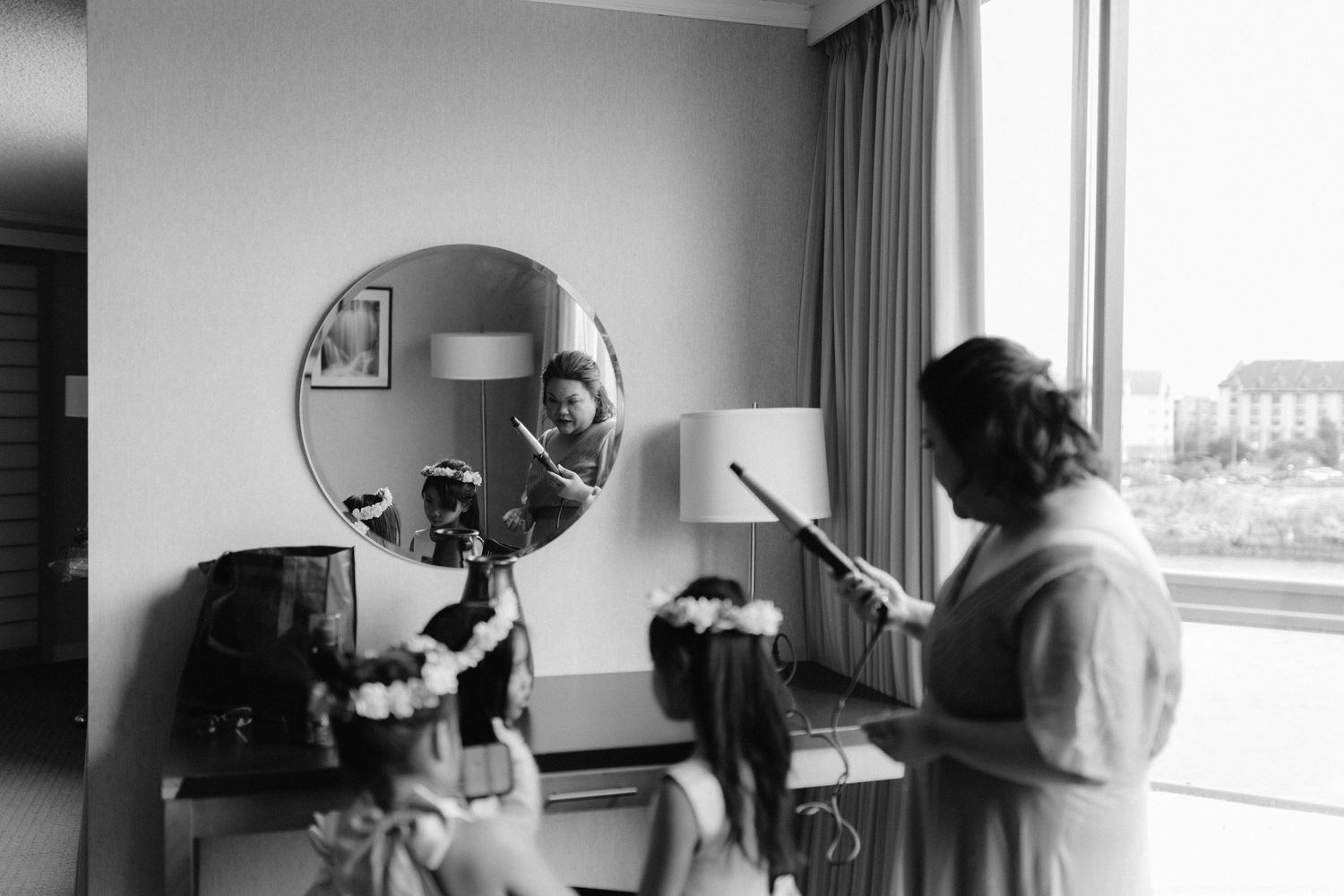 A black and white photo showing preparation activities in a hotel room with natural lighting.