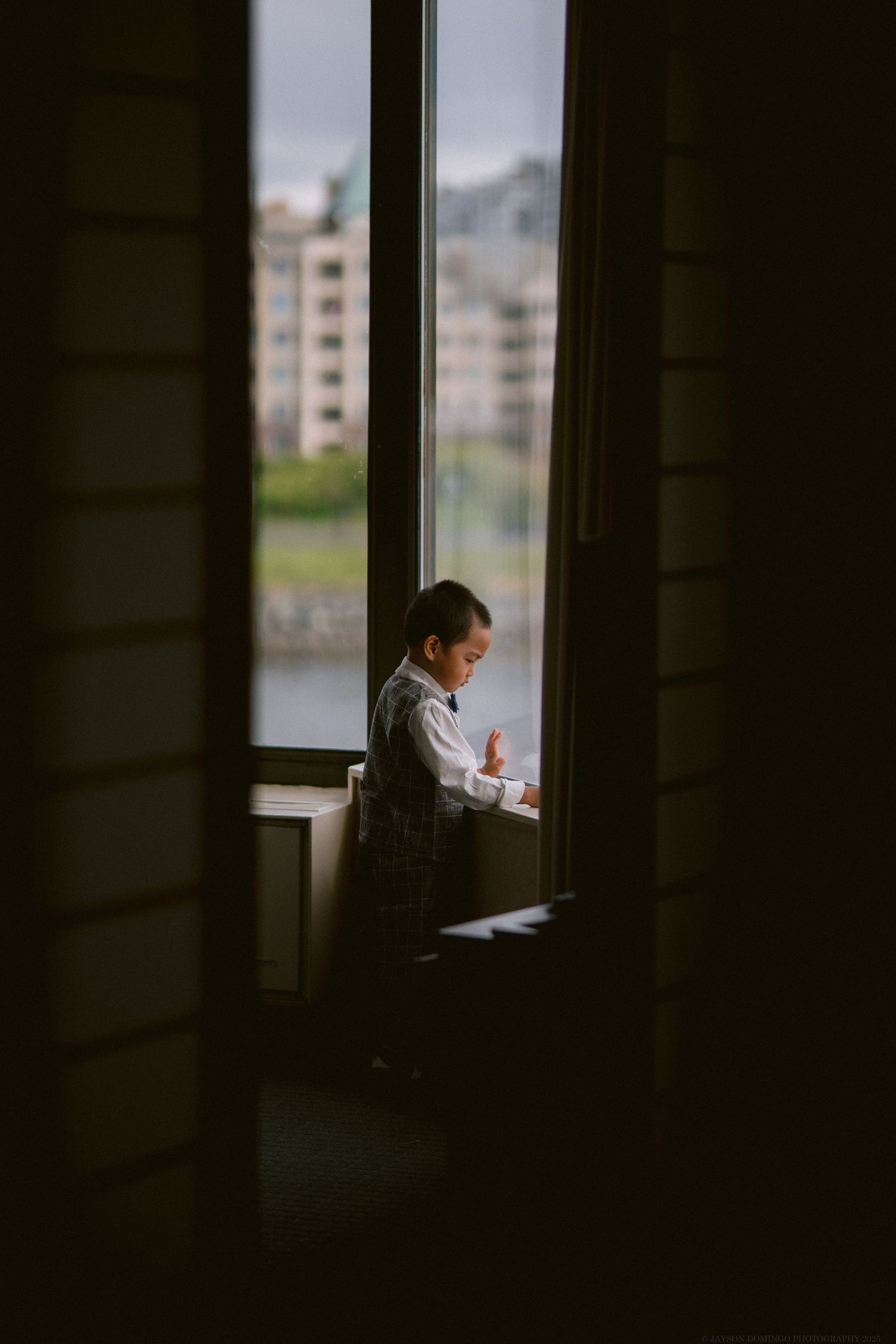 Silhouette of a small child sitting by a window in moody lighting.