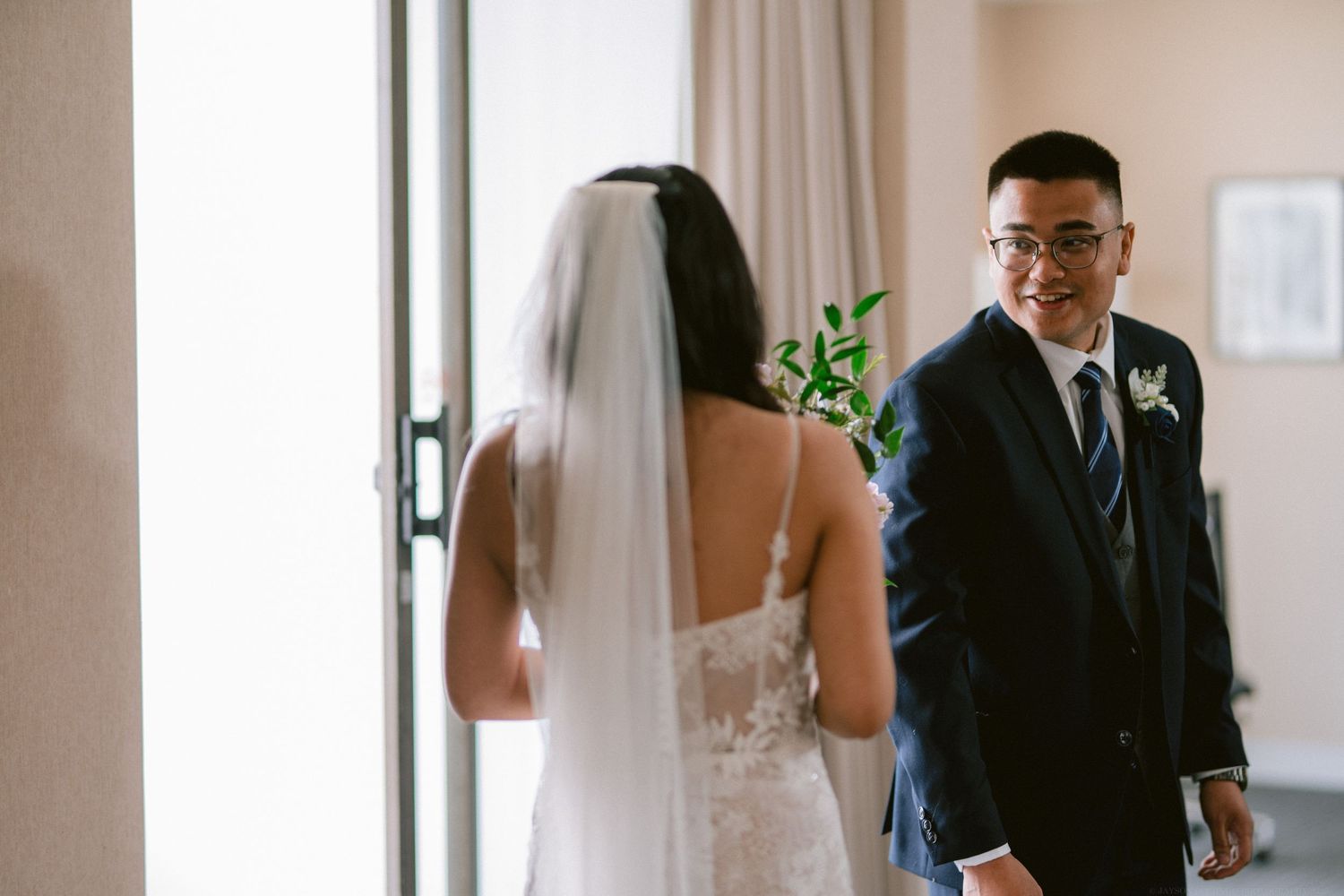 A first look moment between wedding couple in a bright indoor setting.