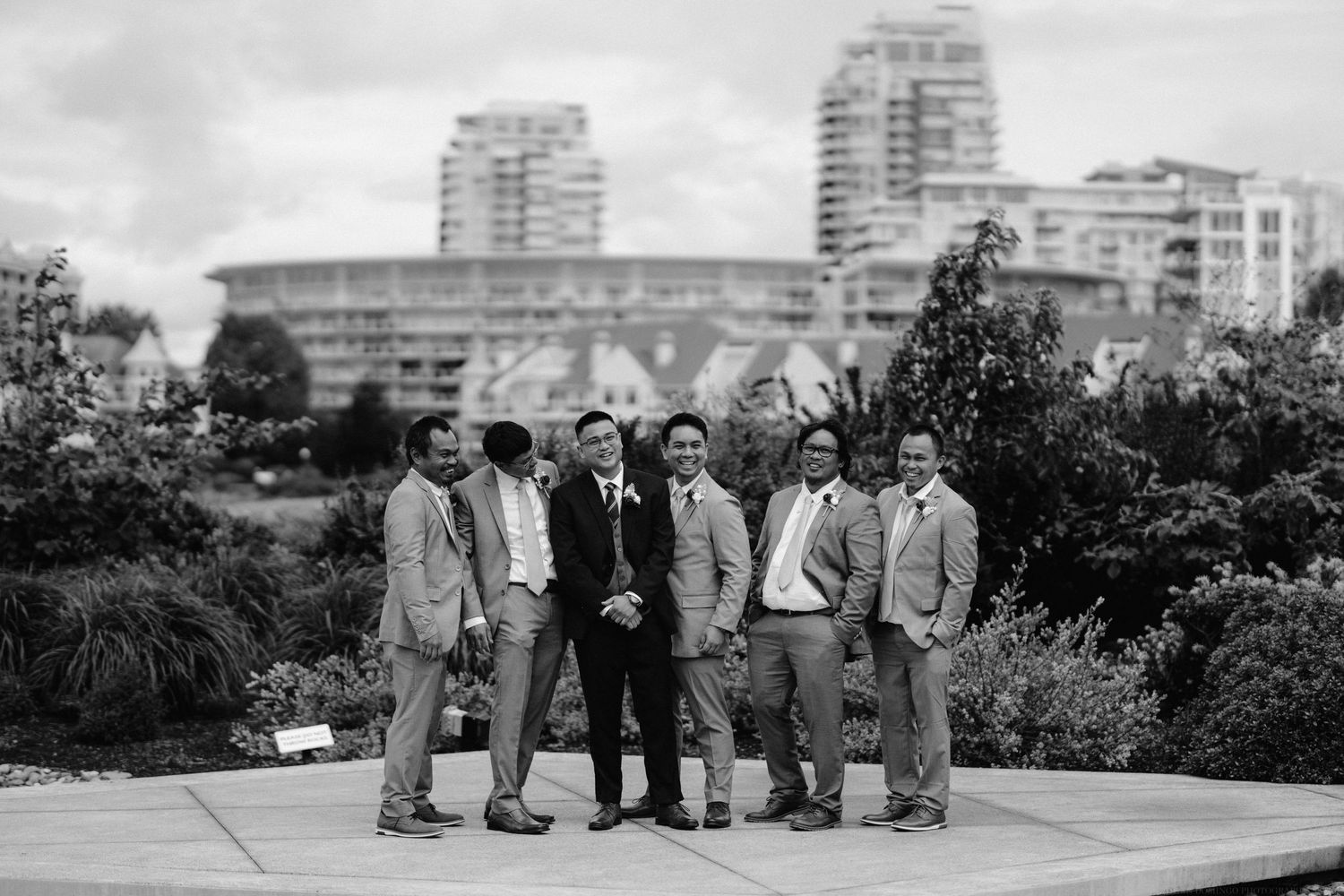 A wedding party poses for a portrait with city buildings in the background.