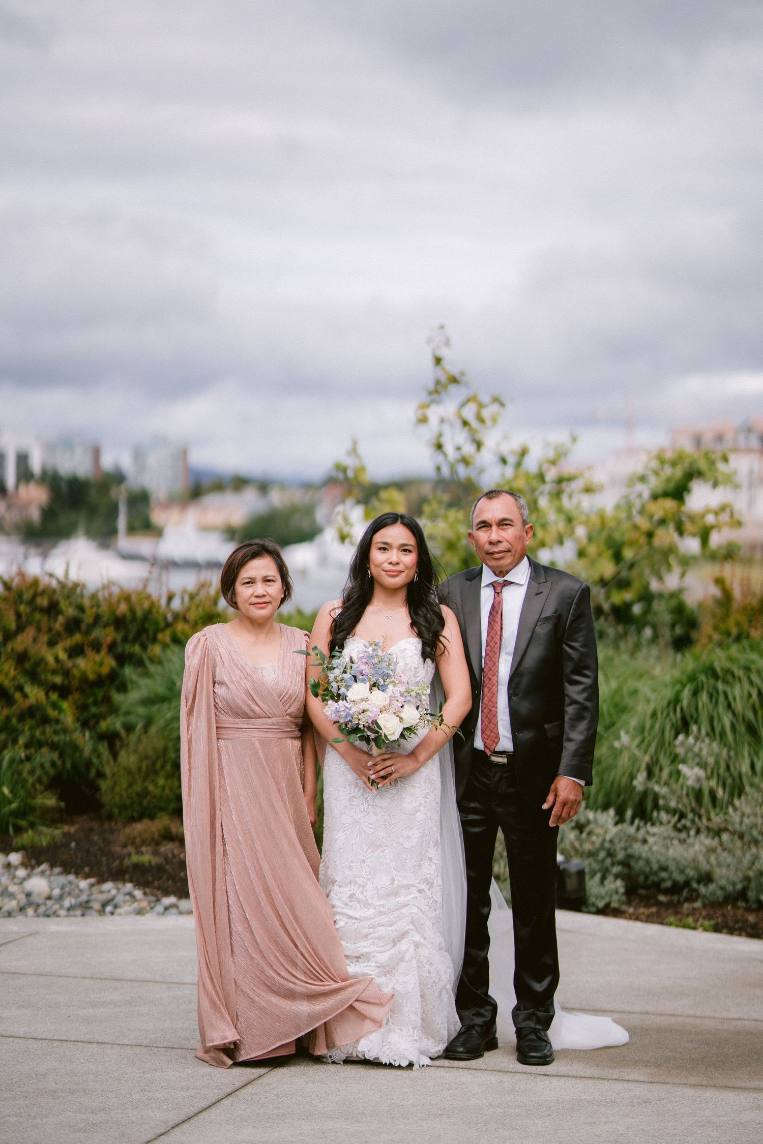 A wedding party poses outdoors against a city skyline backdrop with elegant formal attire.