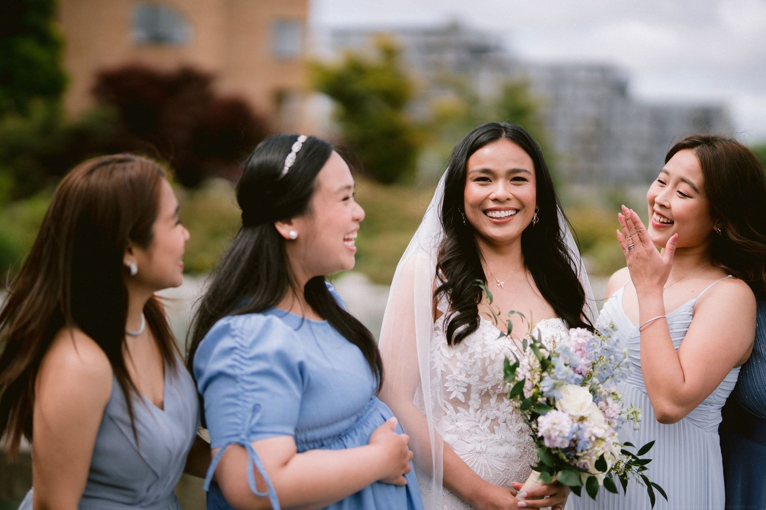 Bridal party in blue dresses sharing a joyful moment outdoors.