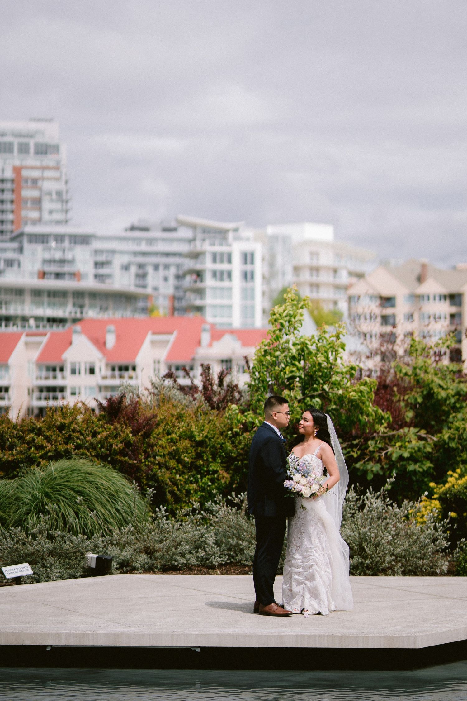 Newlywed couple standing on platform with cityscape background.