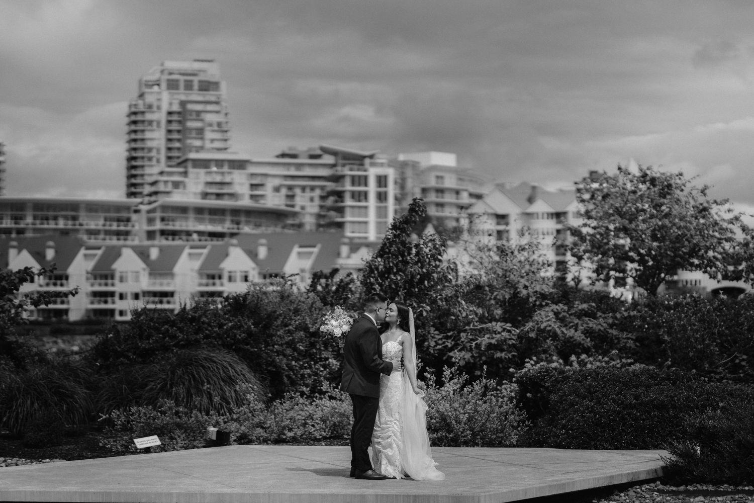 Black and white photo of newlyweds standing against a cityscape backdrop.