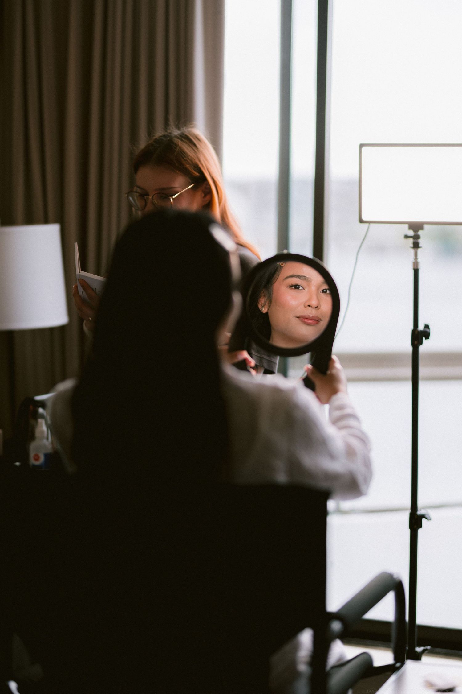 Behind the scenes view of wedding preparation in a hotel room with soft lighting.