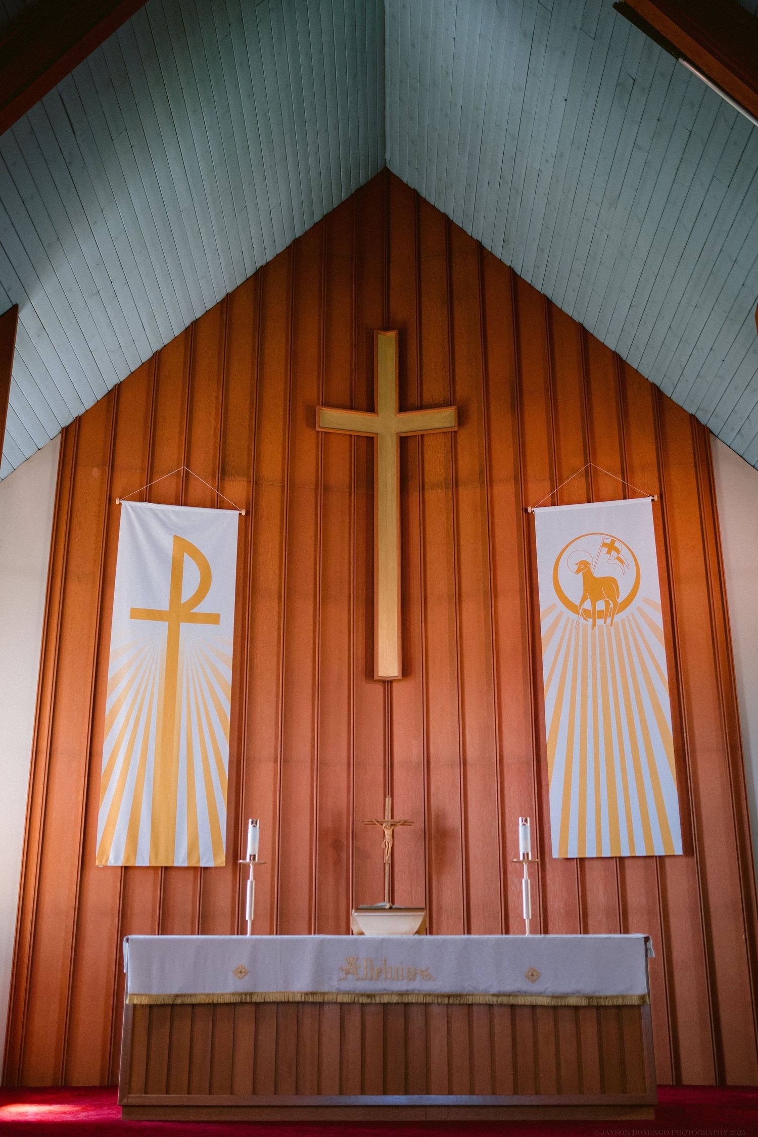 Church altar decorated with golden sunburst banners against wooden paneled walls.