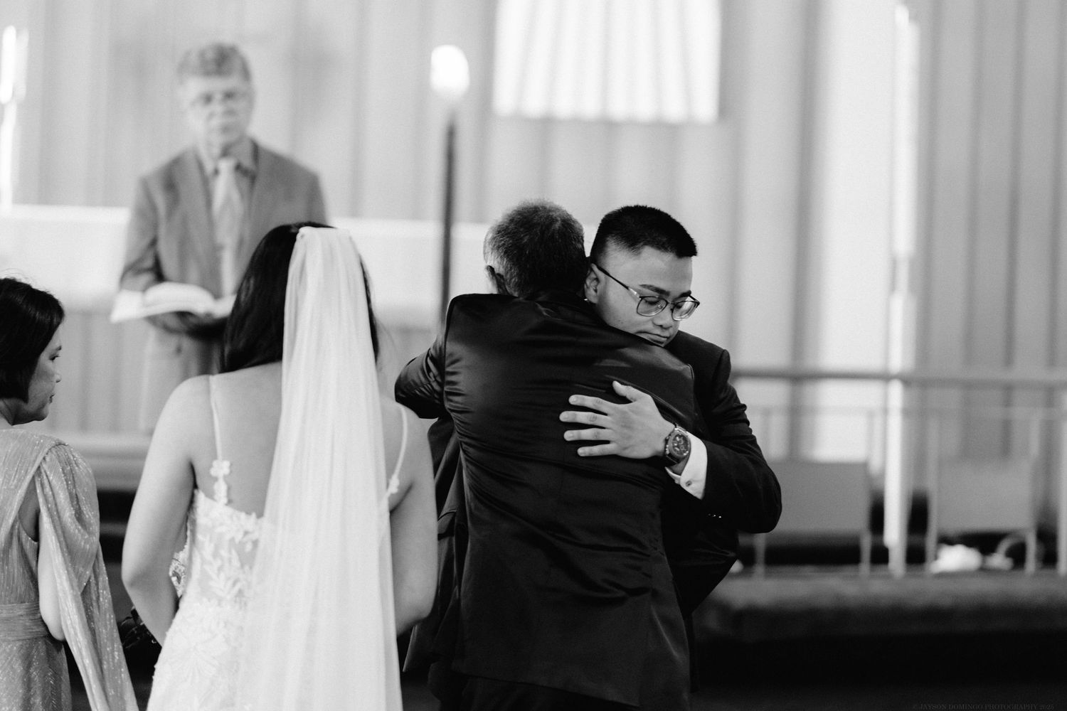 Black and white photo capturing an emotional embrace during a wedding ceremony.
