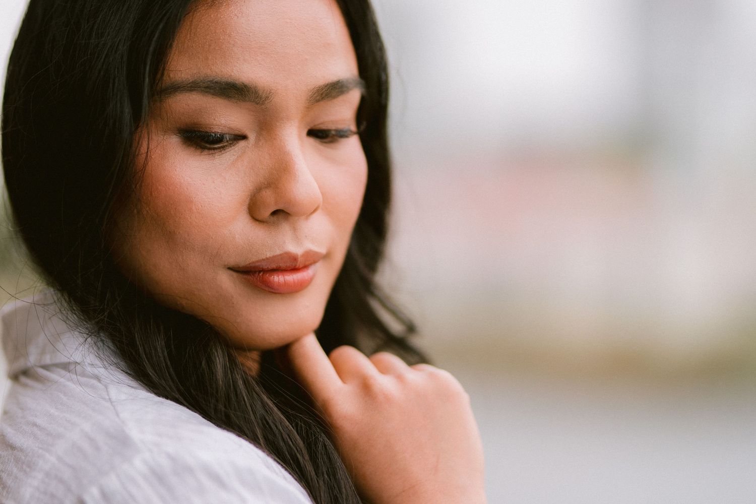 Soft portrait showing gentle contemplative expression against light background.