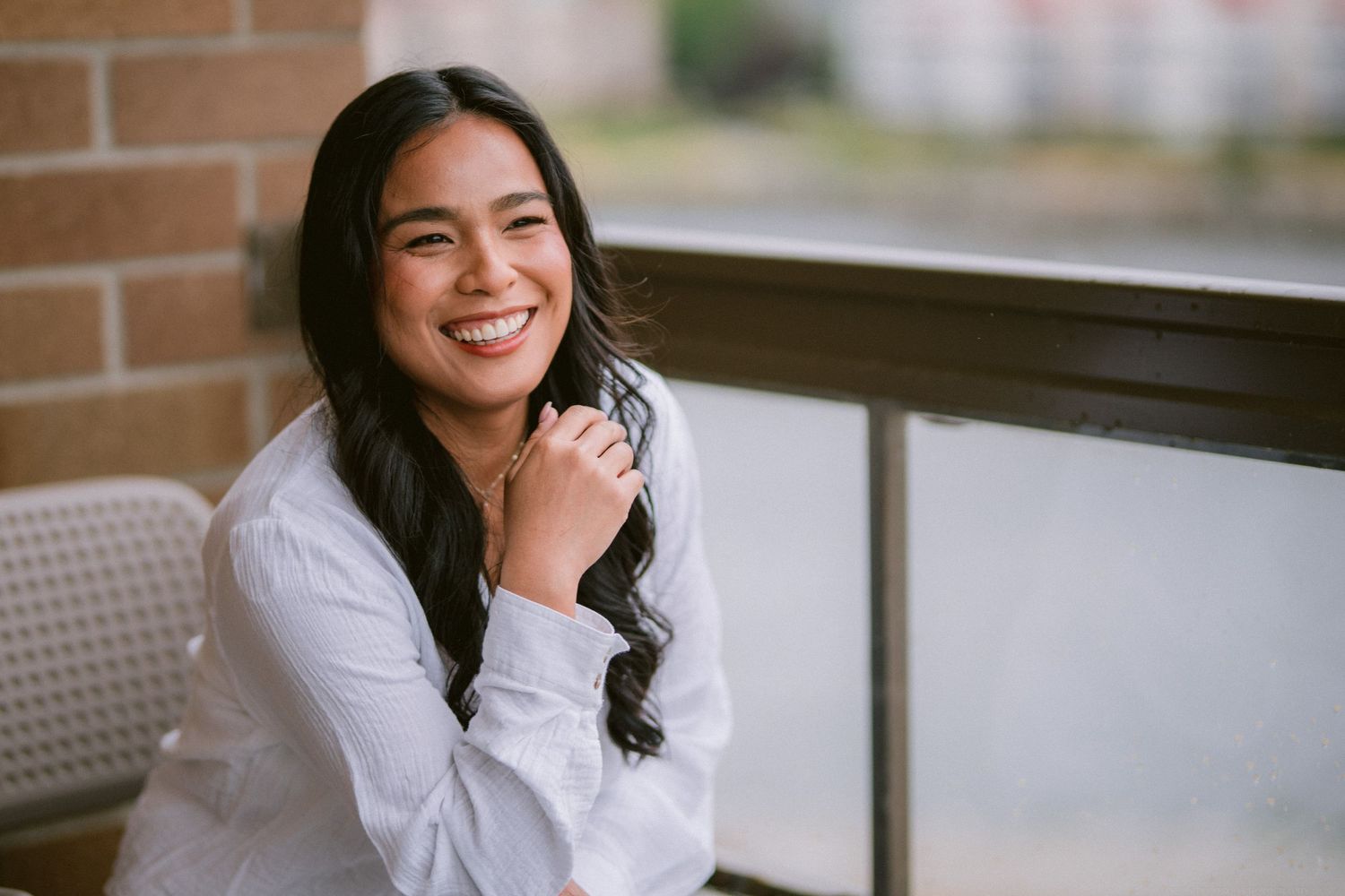 Candid portrait of a woman in white shirt sitting by a window.