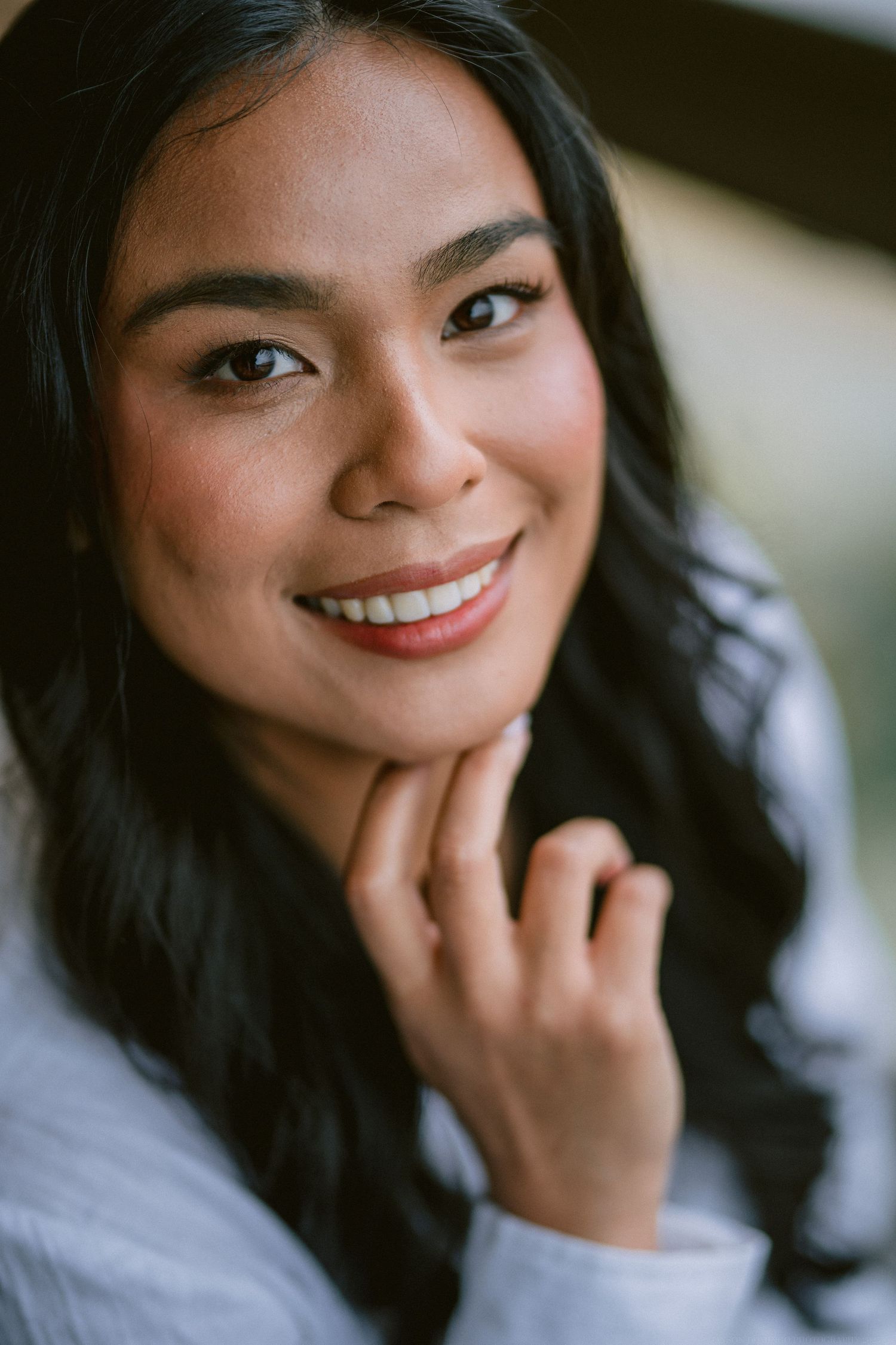 Portrait of a woman in white wearing natural makeup and smiling warmly.