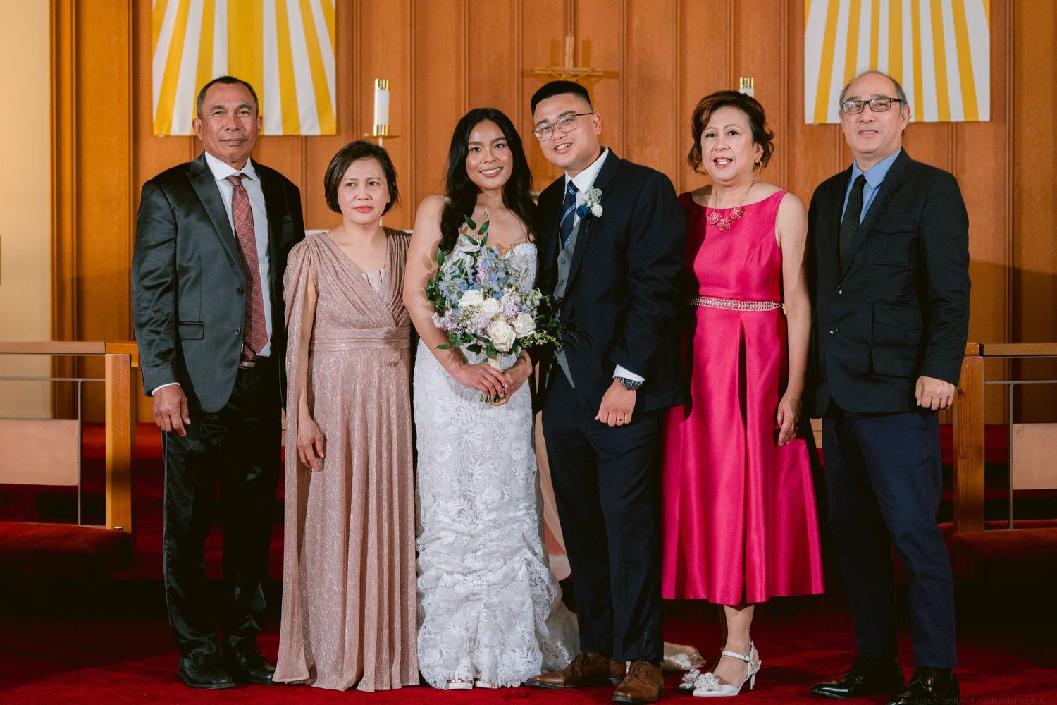Wedding party posing for formal group photo inside church sanctuary.