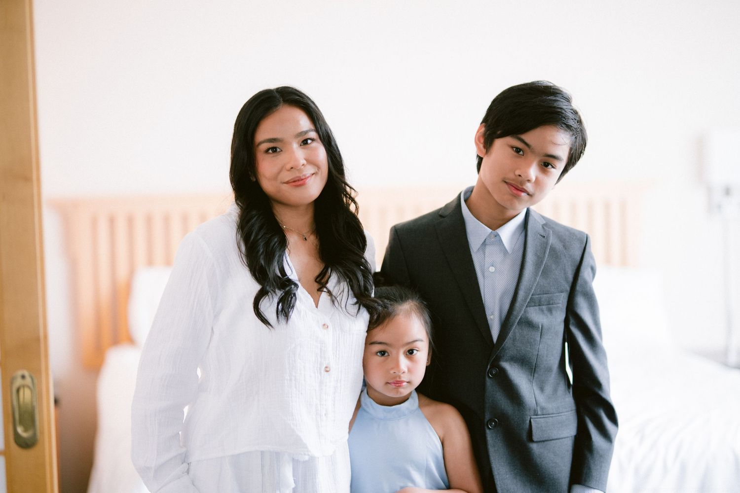 A family in formal attire poses together in a bright interior setting.