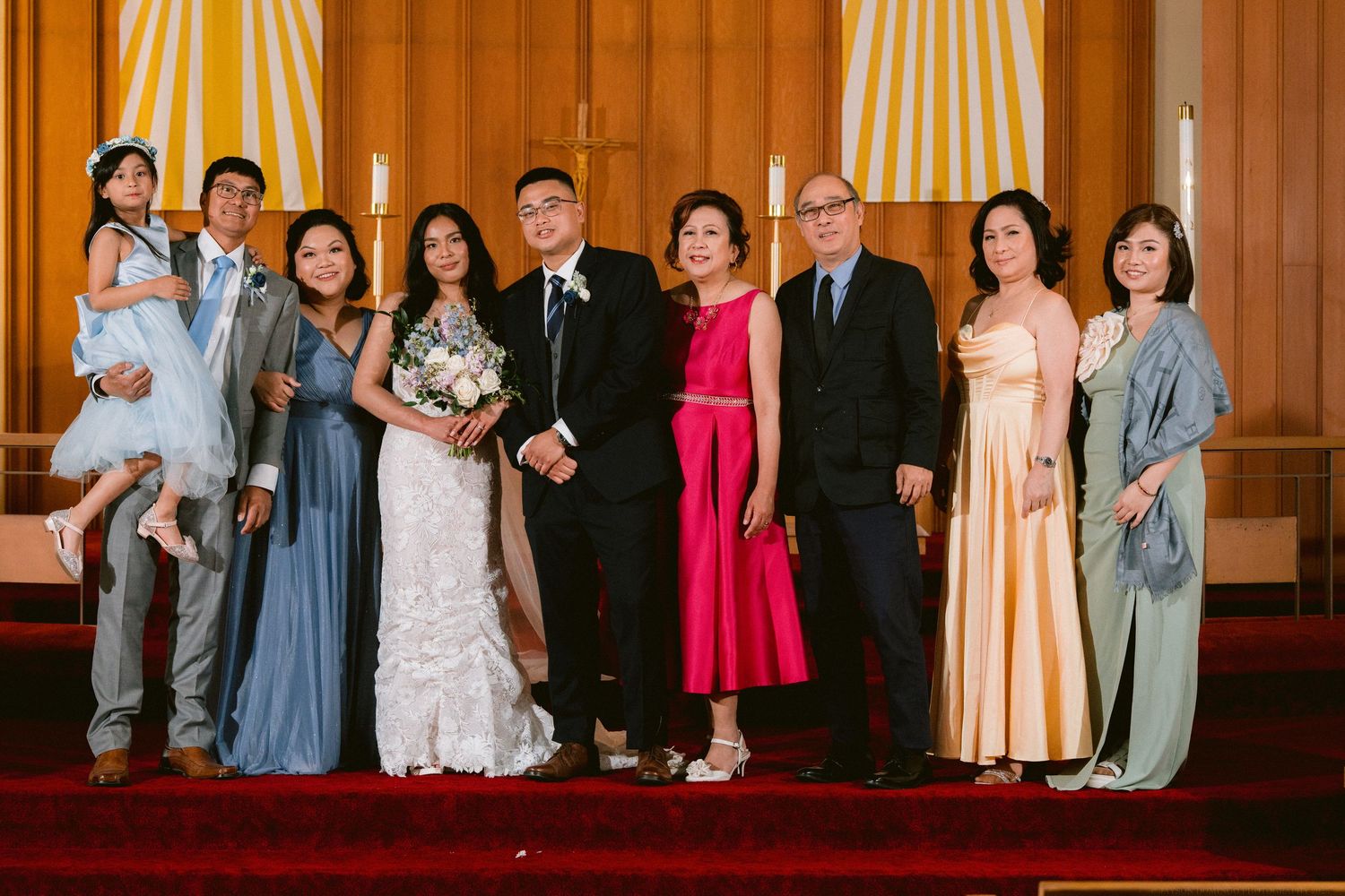 Extended family and wedding party members gathered for formal group photo in church.
