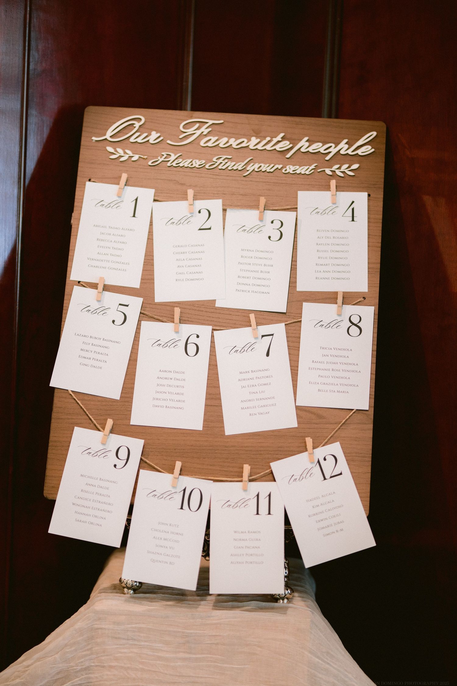 Rustic wooden seating chart display with numbered cards for wedding guests.
