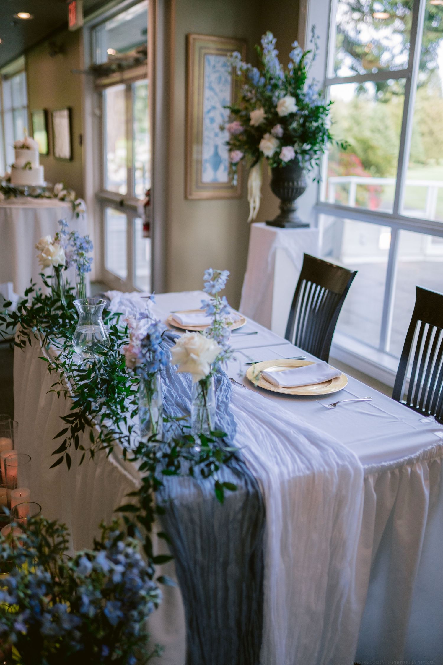 Elegant wedding reception table with blue and white floral arrangements and silk table runner.
