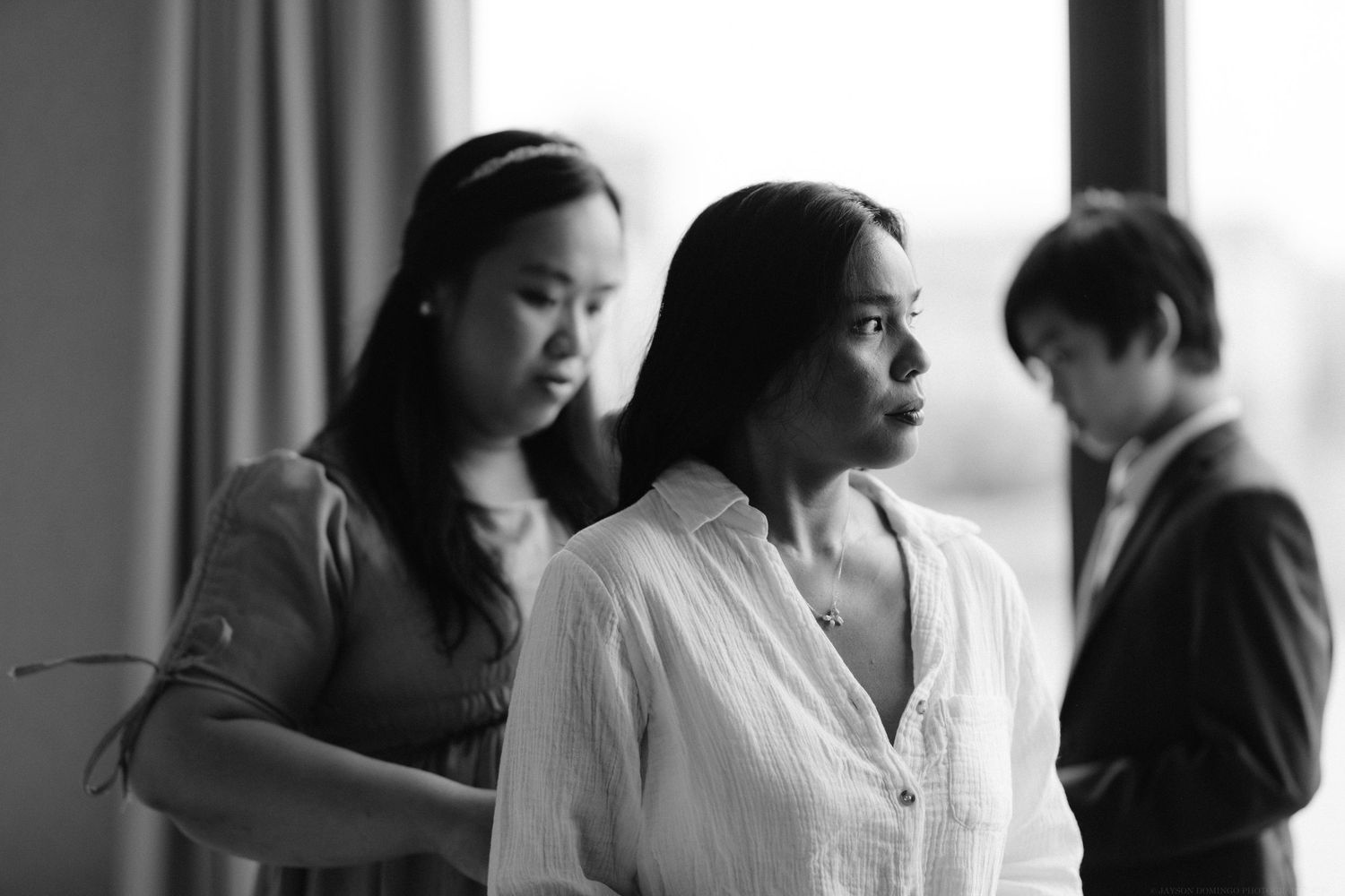 Black and white image of three people getting ready in a room.